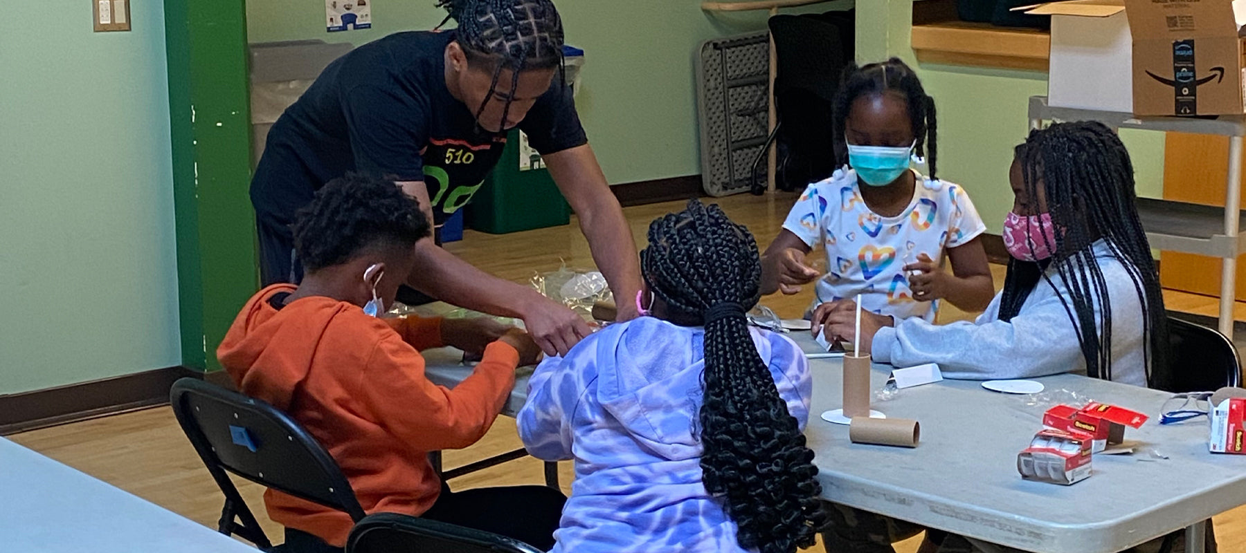 Four children and a teacher doing a science experiment in an Oakland classroom.