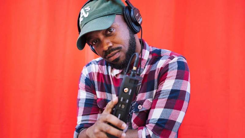 Pen, with recording equipment, wearing headphones and A's hat.