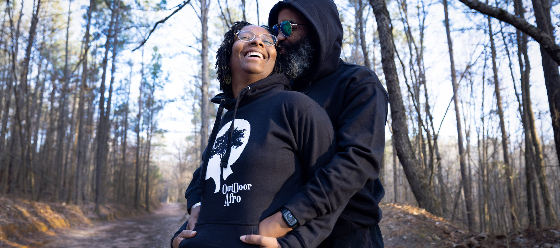 Image of female and male model wearing Outdoor Afro black signature hoodie on hiking trail.
