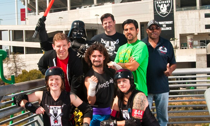 Group photo of people featured in article, in front of the coliseum.