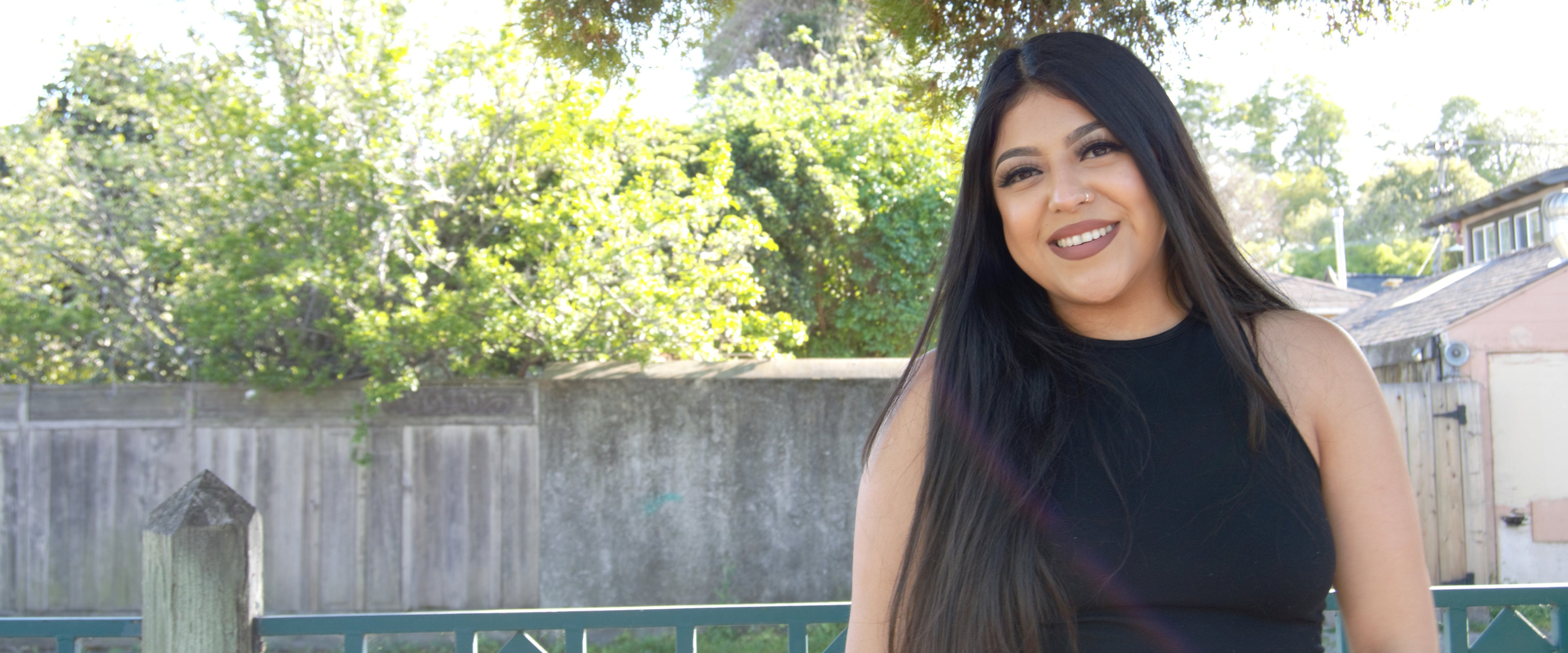 Maria in a back yard, wearing a black tank top