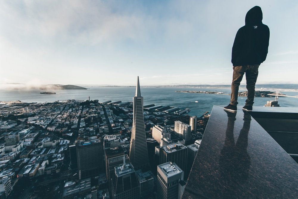 photographer Meez standing on a ledge overlooking city skyline San Francisco