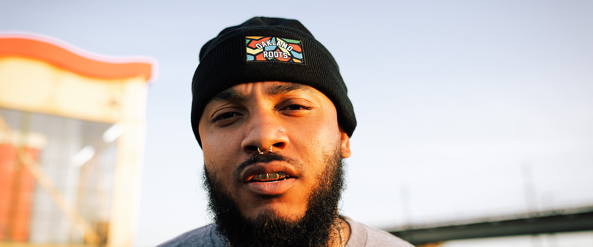 A man wearing a black beanie with full-color Roots SC mosaic logo in the front middle of beanie,