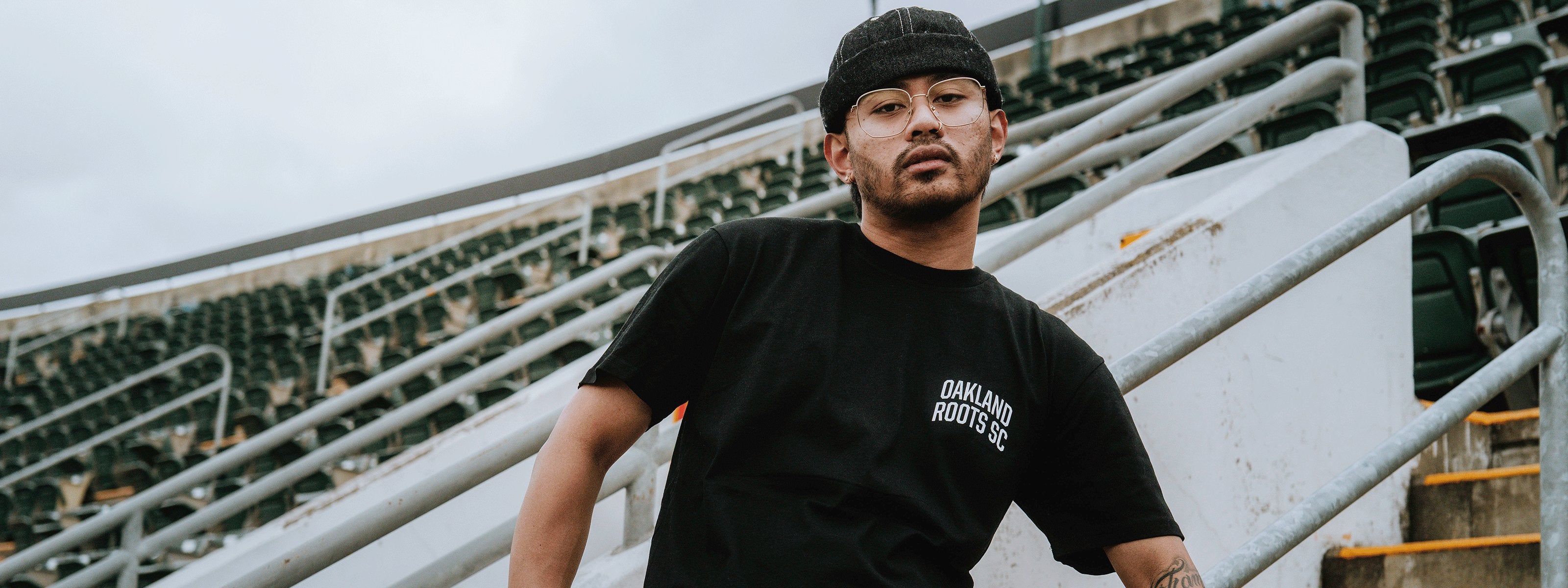 Man wearing a black tee with Oakland Roots Logo.
