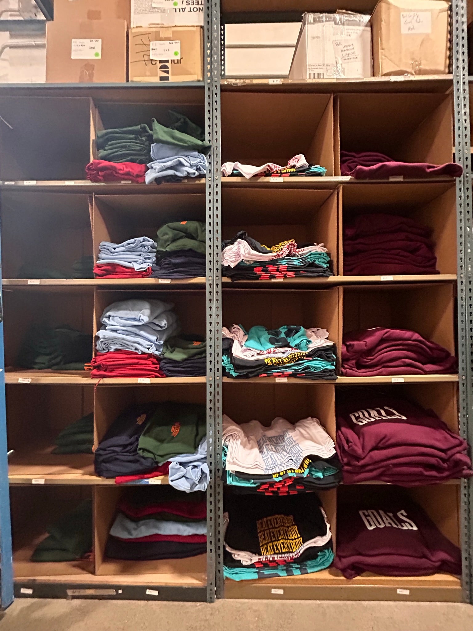 Shelves with cardboard boxes facing out, with shirts folded inside.