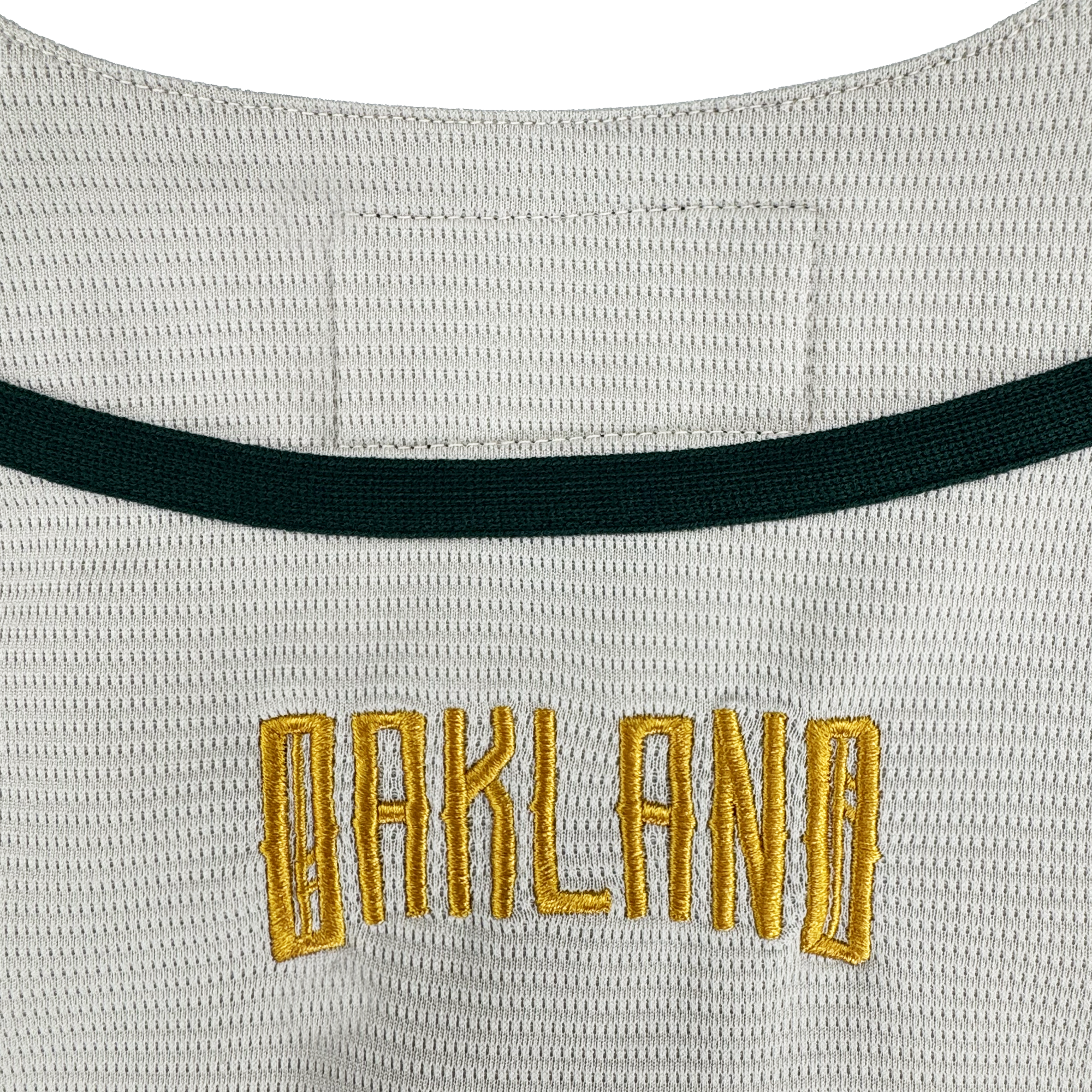 A close-up of the Oakland Ballers Button Up Jersey by Oakland Ballers shows "OAKLAND" in gold block letters with a black border, below a dark green stripe, representing the Pioneer League’s professional baseball team.