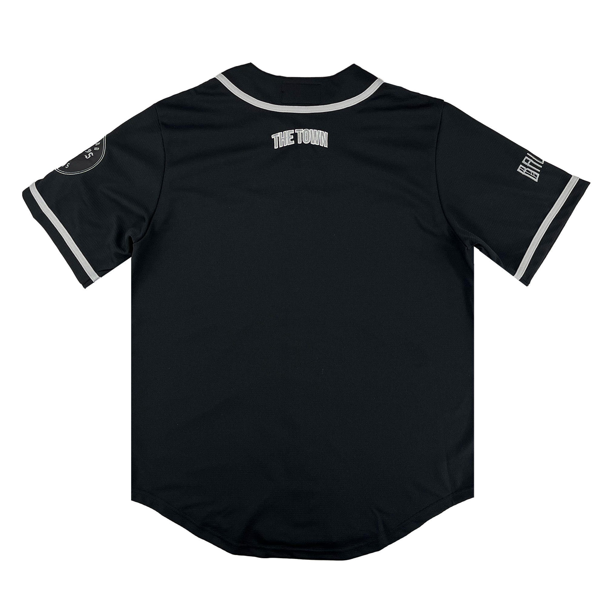 The Oakland Ballers Button Up Jersey by Oakland Ballers features "THE TOWN" on the upper back, white-trimmed sleeves, a patch on the left sleeve, and Oakland Ballers team lettering on the right sleeve. Shown from the back on a white background.