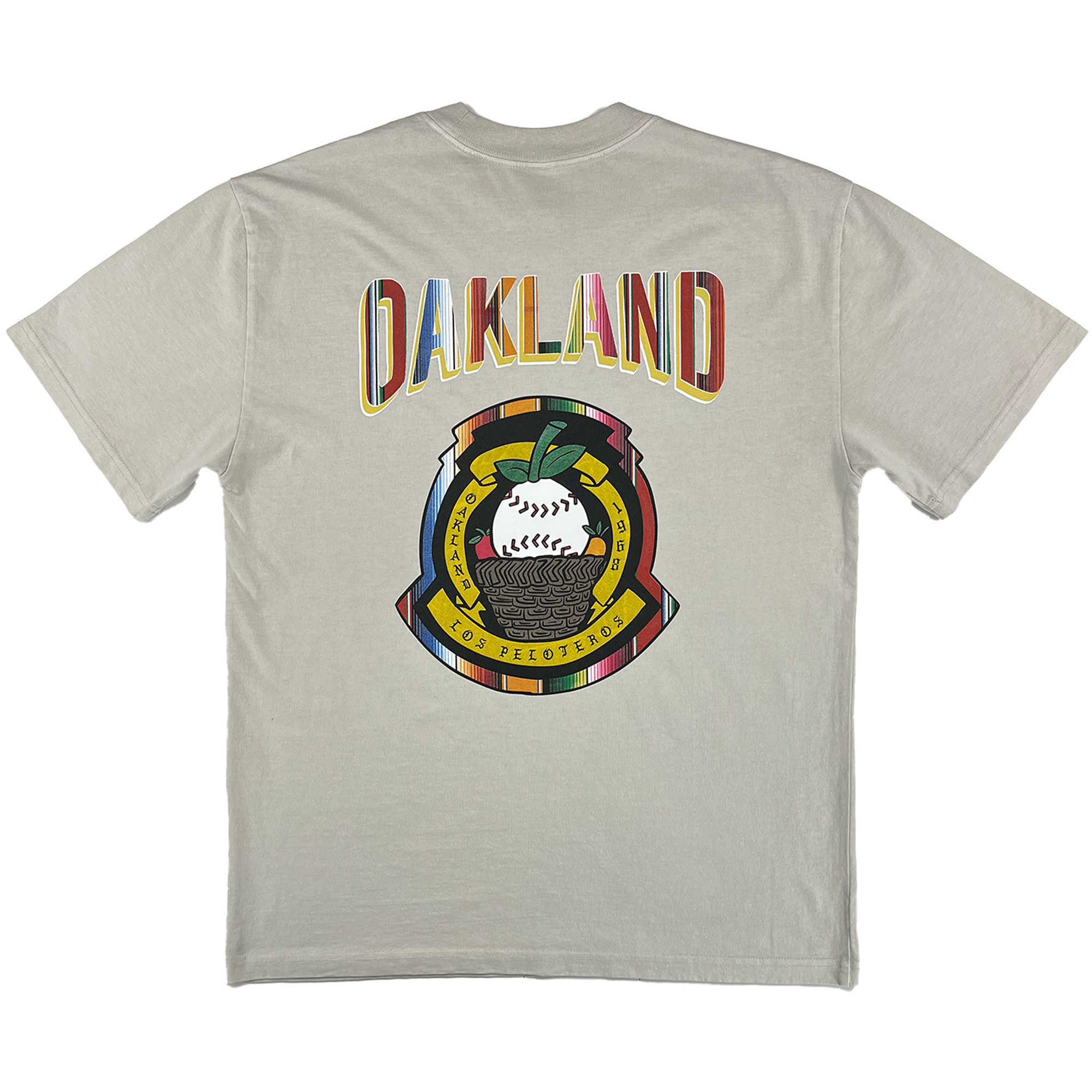 The Oakland Beisbol Heavy Tee by Oakland Ballers features “OAKLAND” in rainbow block letters on the back, with a vibrant patch below showing "LOS PELOTEROS," a baseball, and an elephant in bright celebratory colors.