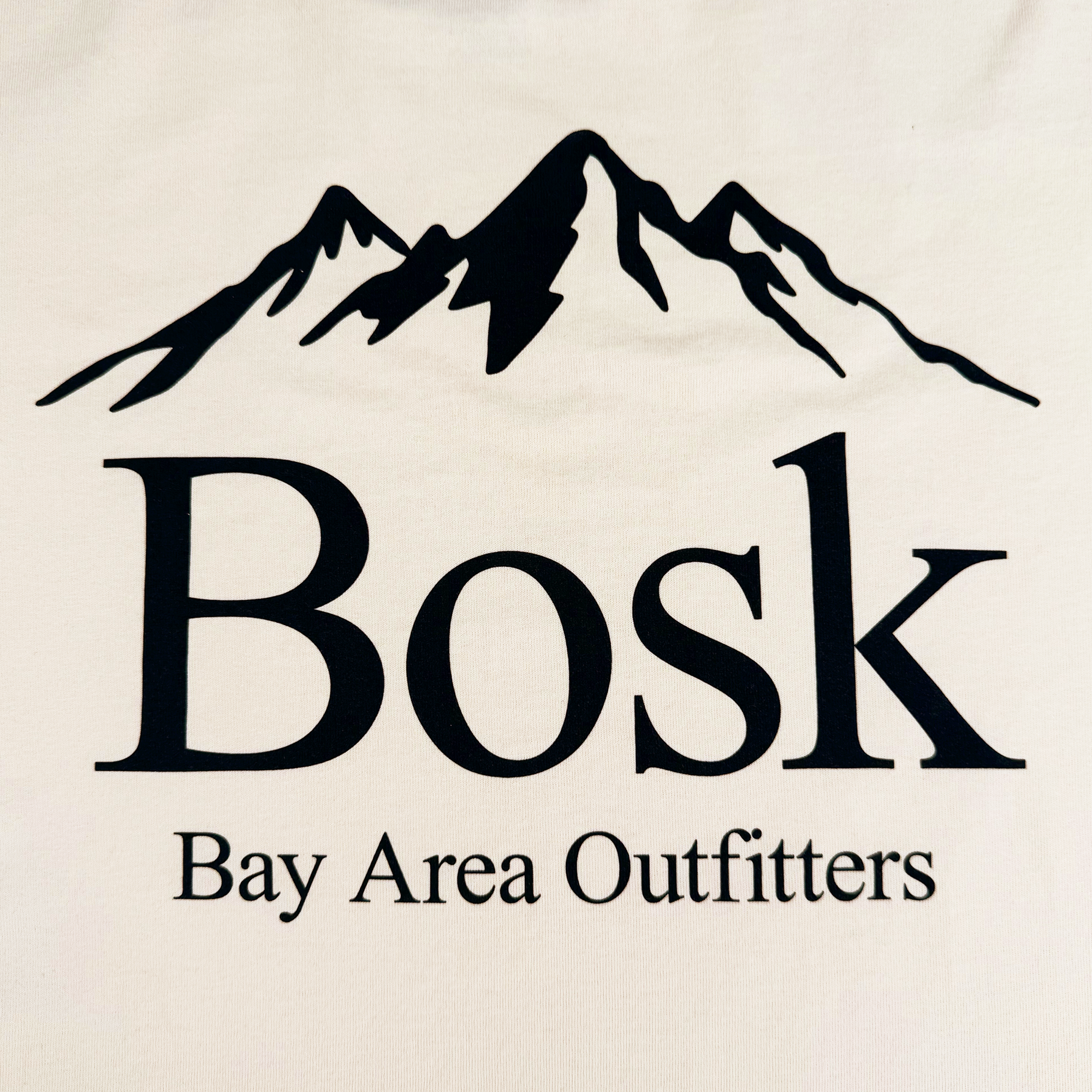 A stylized black mountain peak logo with the bold word "BOSK" and "Bay Area Outfitters" in smaller text below. The outdoor-themed design is perfect for a heavyweight cotton oversized Bosk Outdoors Tee.