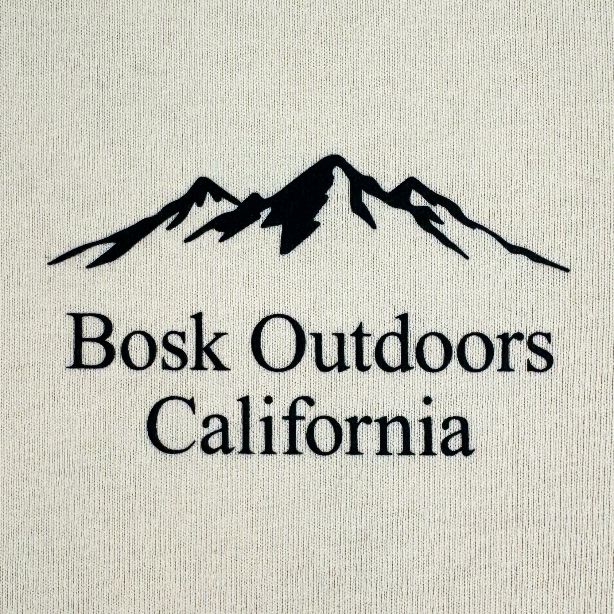 The cream background features "BOSK Outdoors California" text, with a black silhouette of a mountain range above. This evokes an outdoor theme reminiscent of the Bosk Outdoors Tee, an oversized men's heavyweight cotton t-shirt perfect for rugged adventures.