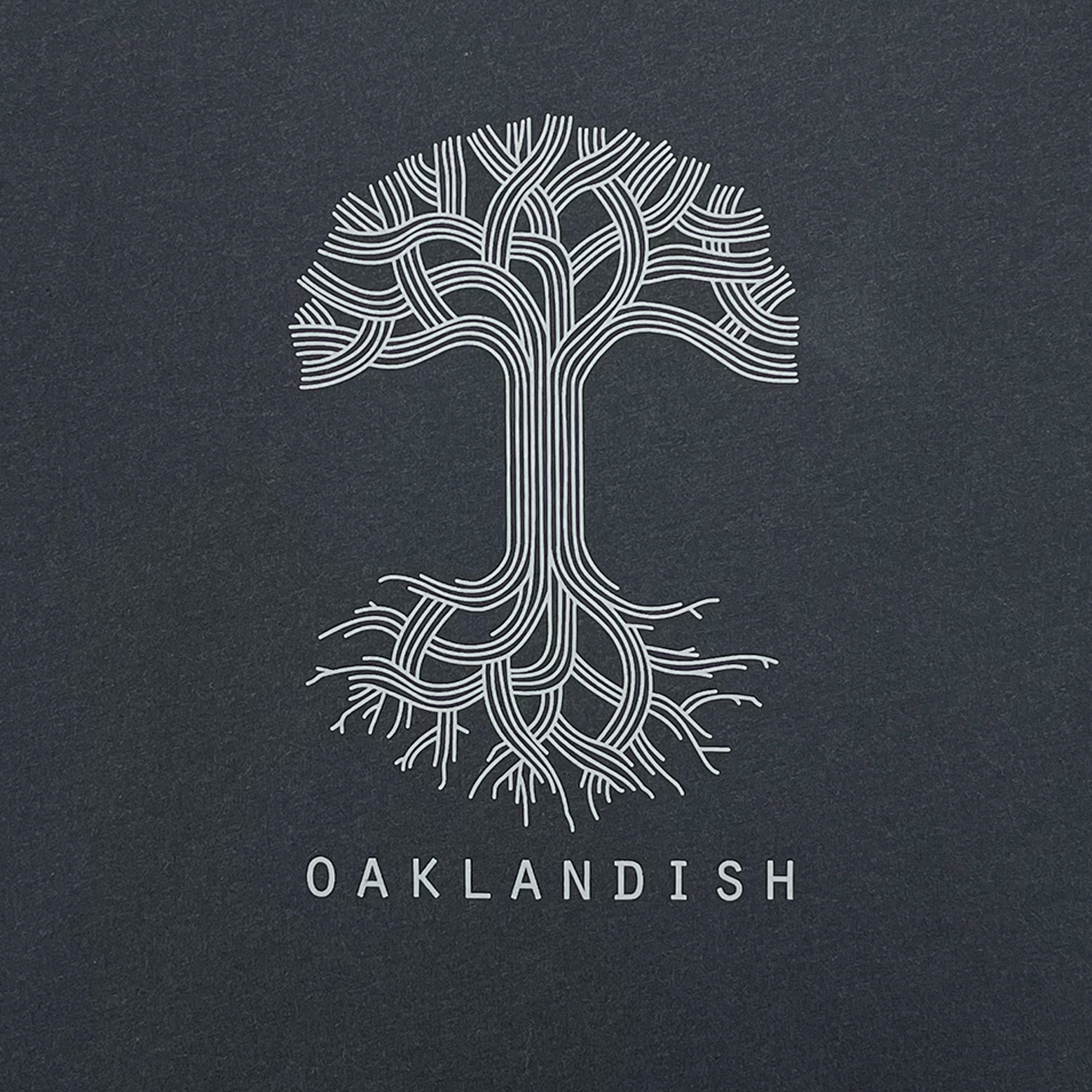 Close-up of an Oaklandish tree graphic with an Oaklandish wordmark on a heather black t-shirt.