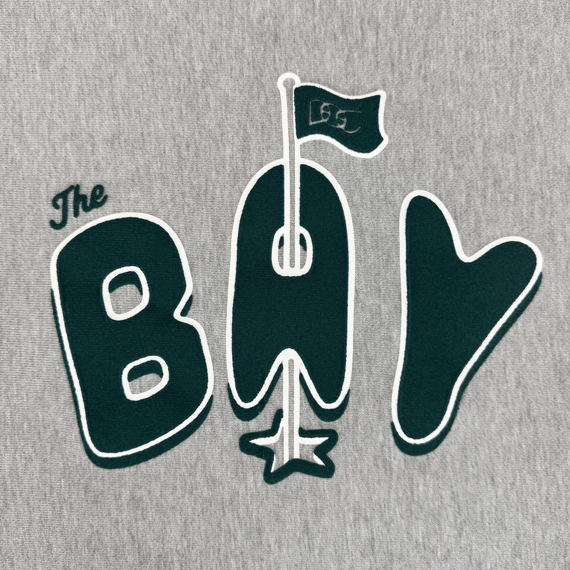 Oaklandish’s The Bay Flag Crew By DOC is a gray premium heavyweight fleece with “The BAY” in dark green, white-outlined letters. The “A” forms an electric guitar with a flag reading "est" and a star at the base—playful and bold from The Bay Collection.