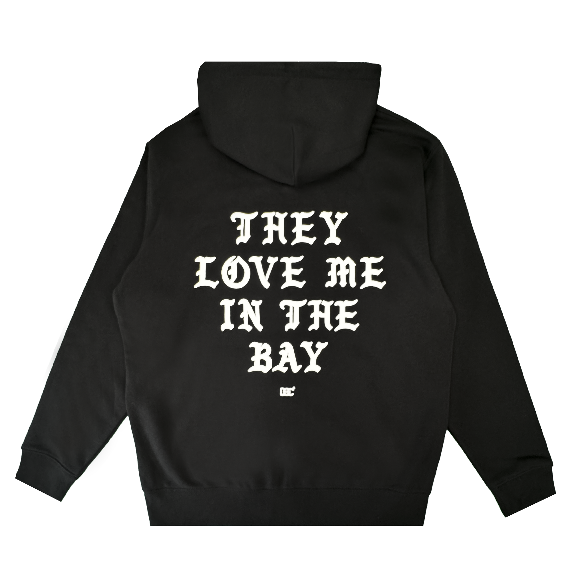 A black heavyweight fleece zip hoodie from By DOC’s They Love Me Zip collection, featuring white gothic-style text on the back that reads “THEY LOVE ME IN THE BAY” with a small white logo beneath it, laid flat on a white background.