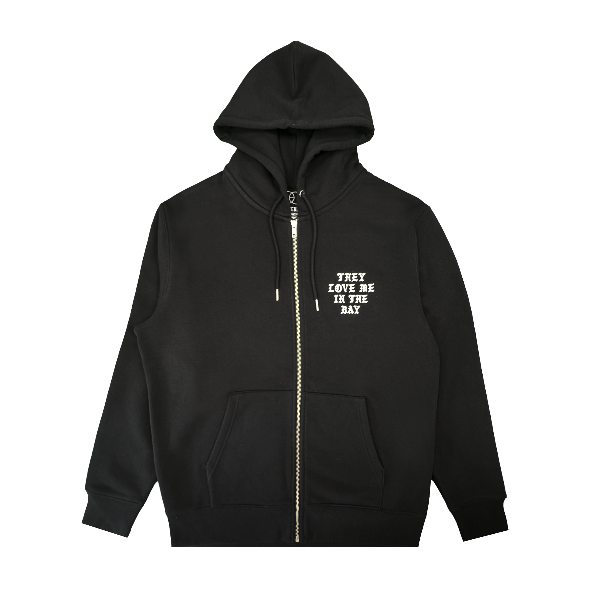A black They Love Me Zip By Doc hoodie from By DOC, made with heavyweight fleece and designed with front pockets and a hood. The left chest features white, all-caps text that reads “THEY LOVE ME IN THE BAY.” The hoodie is displayed flat on a white background.