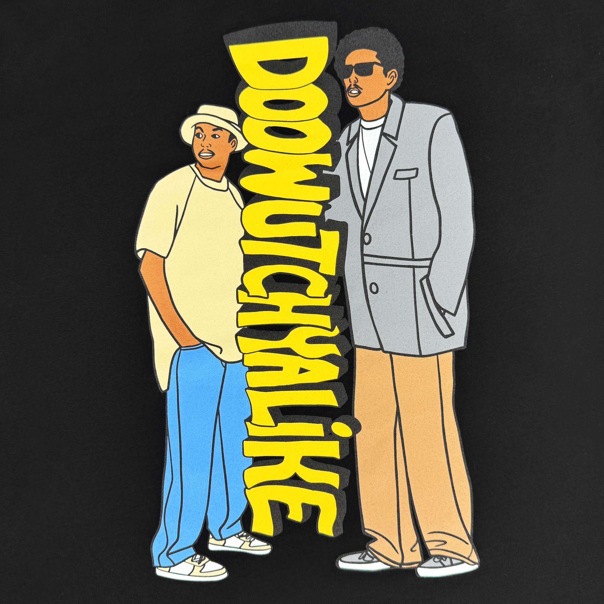 Two figures with 90s flair stand against a black backdrop on the Oaklandish "Doowutchyalike" Tee. One wears a beige hat and yellow shirt, the other a gray suit with sunglasses; bold yellow text spells "DOOWUTCHYALIKE" vertically, capturing the essence of Digital Underground.
