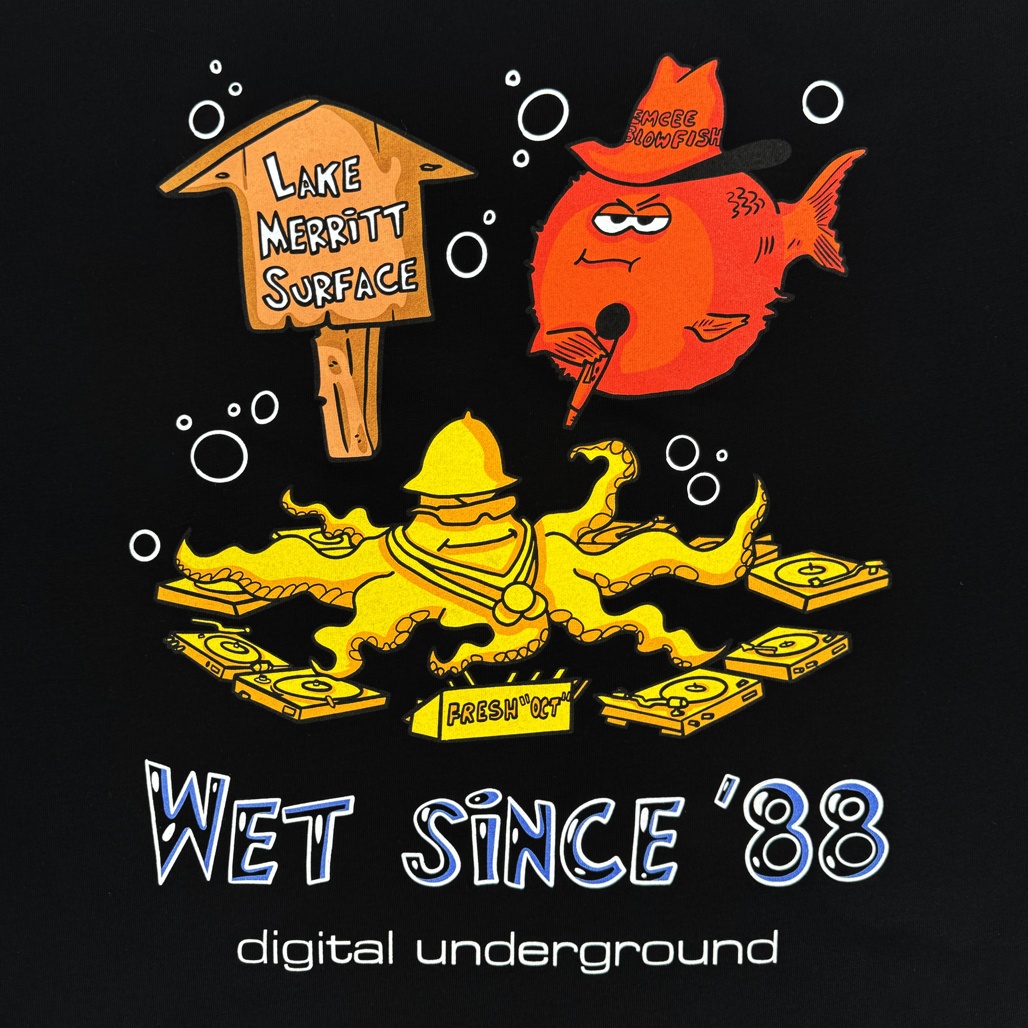 A cartoon octopus DJ in shades spins records underwater with "Fresh Out" text. Nearby, Shock G Humpfish swims past a "Lake Merritt Surface" sign in Oakland, surrounded by bubbles. The black backdrop reads "Wet since '88 Digital Underground's Underwater Rimes." Product: Wet Since '88 Tee by Oaklandish.