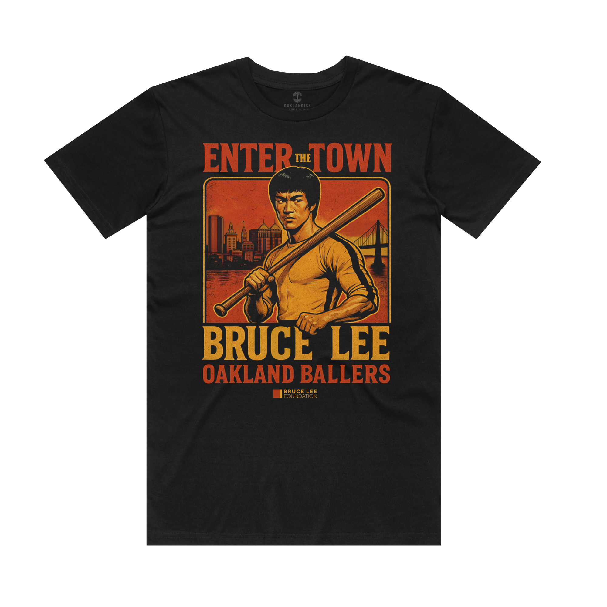 The Enter the Town Tee by Oakland Ballers is a black T-shirt with Bruce Lee holding a baseball bat, city skyline and bridge behind him. "ENTER THE TOWN" headlines the design, with bold orange/yellow text supporting youth mental wellness.