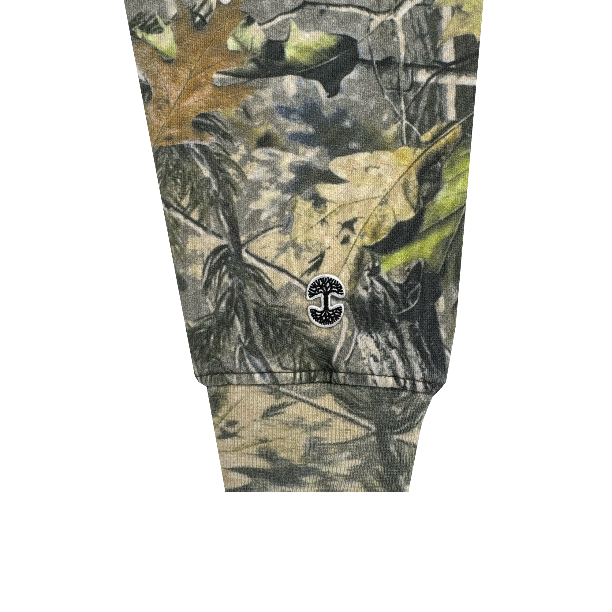 A close-up of the Foliage Hoodie by Oaklandish shows a sleeve cuff with a wood camo pattern in green, brown, and tan. Near the cuff is a small black embroidered Oaklandish tree logo with two mirrored 'C' shapes in a circular design.