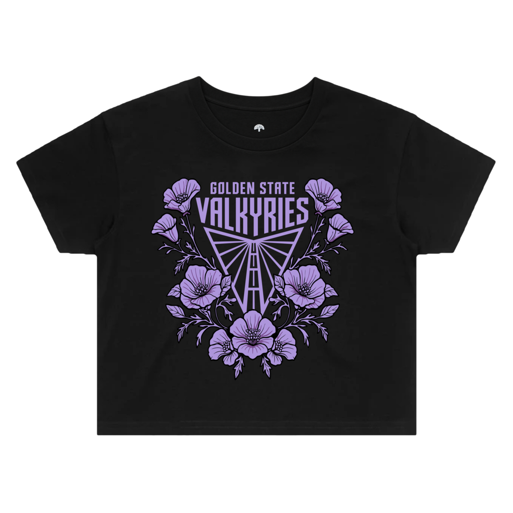 The GSV Women’s Poppies Crop Tee is a black cropped t-shirt featuring a light purple graphic of a stylized bridge above the text “GOLDEN STATE VALKYRIES,” all surrounded by blooming poppy flowers.