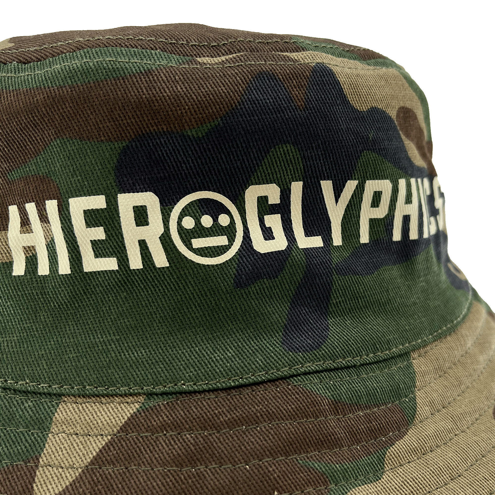 Close-up of Hieroglyphics Hip Hop Crew wordmark on the front crown of a Woodlands Camo bucket hat. 