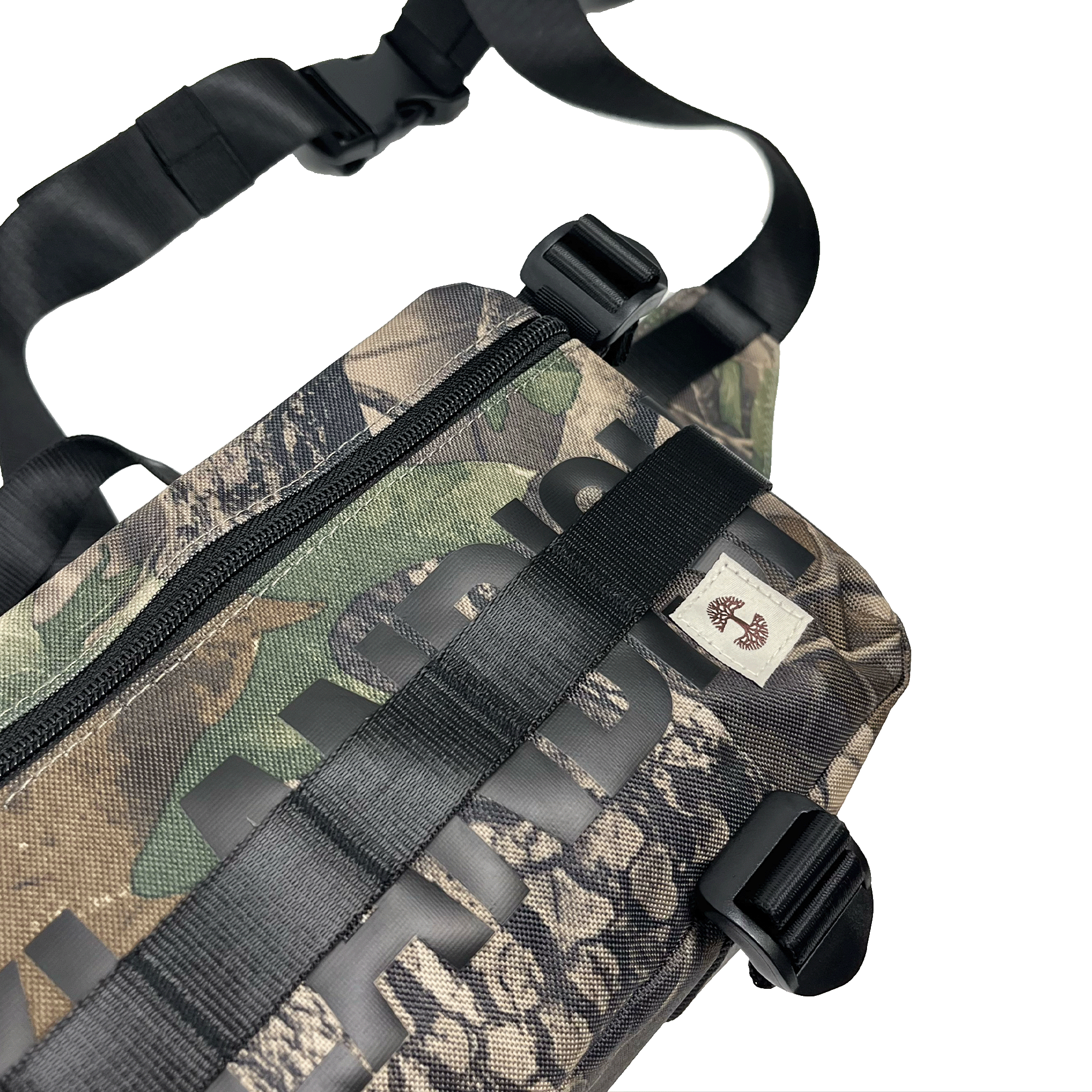 Top side view of a camo pattern cross-body bag with front zipper and large black Oakladish wordmark and Oaklandish tree logo patch.