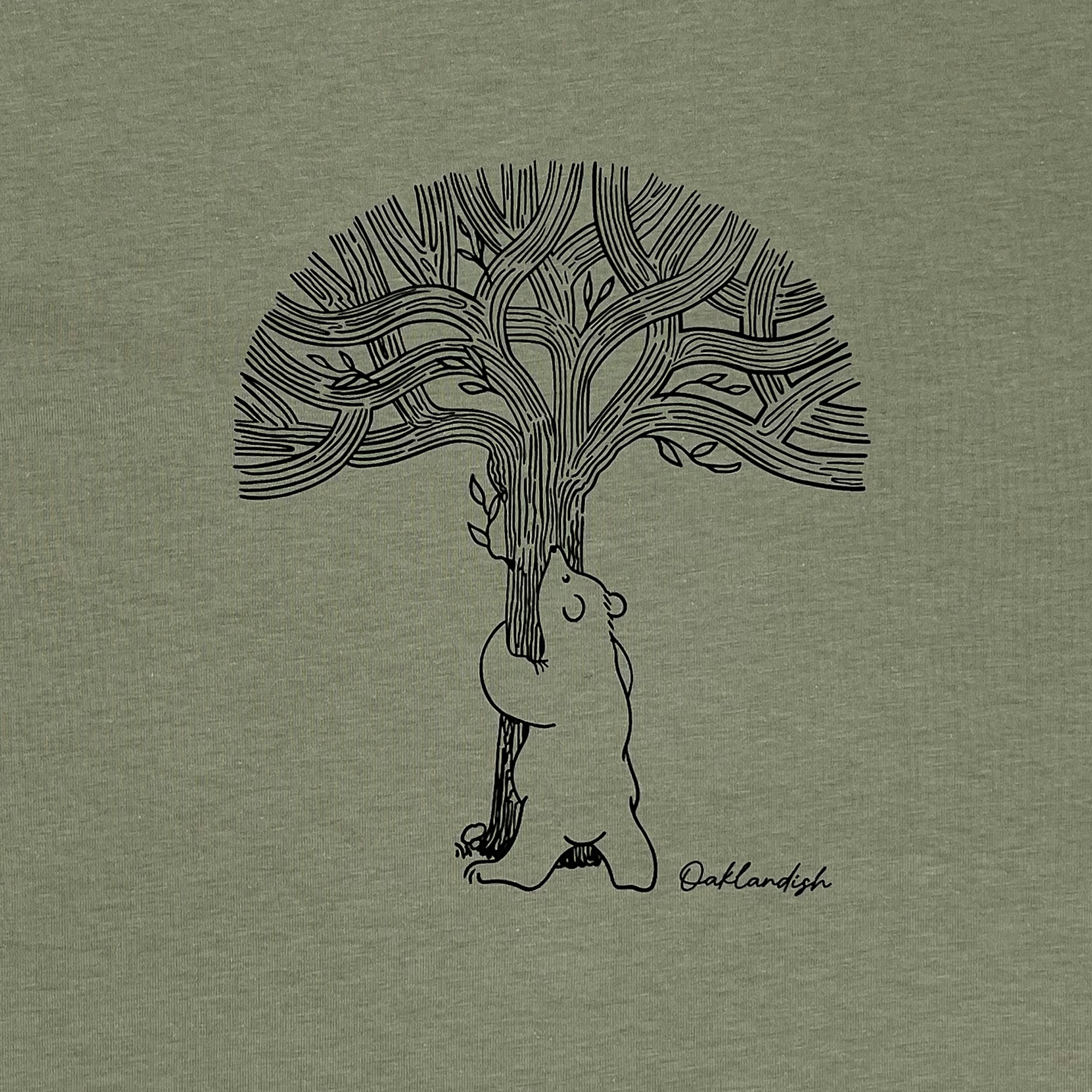 Close-up of line graphic featuring a bear hugging a tree representing Oaklandish with Oaklandish wordmark on Eucalyptus green t-shirt.