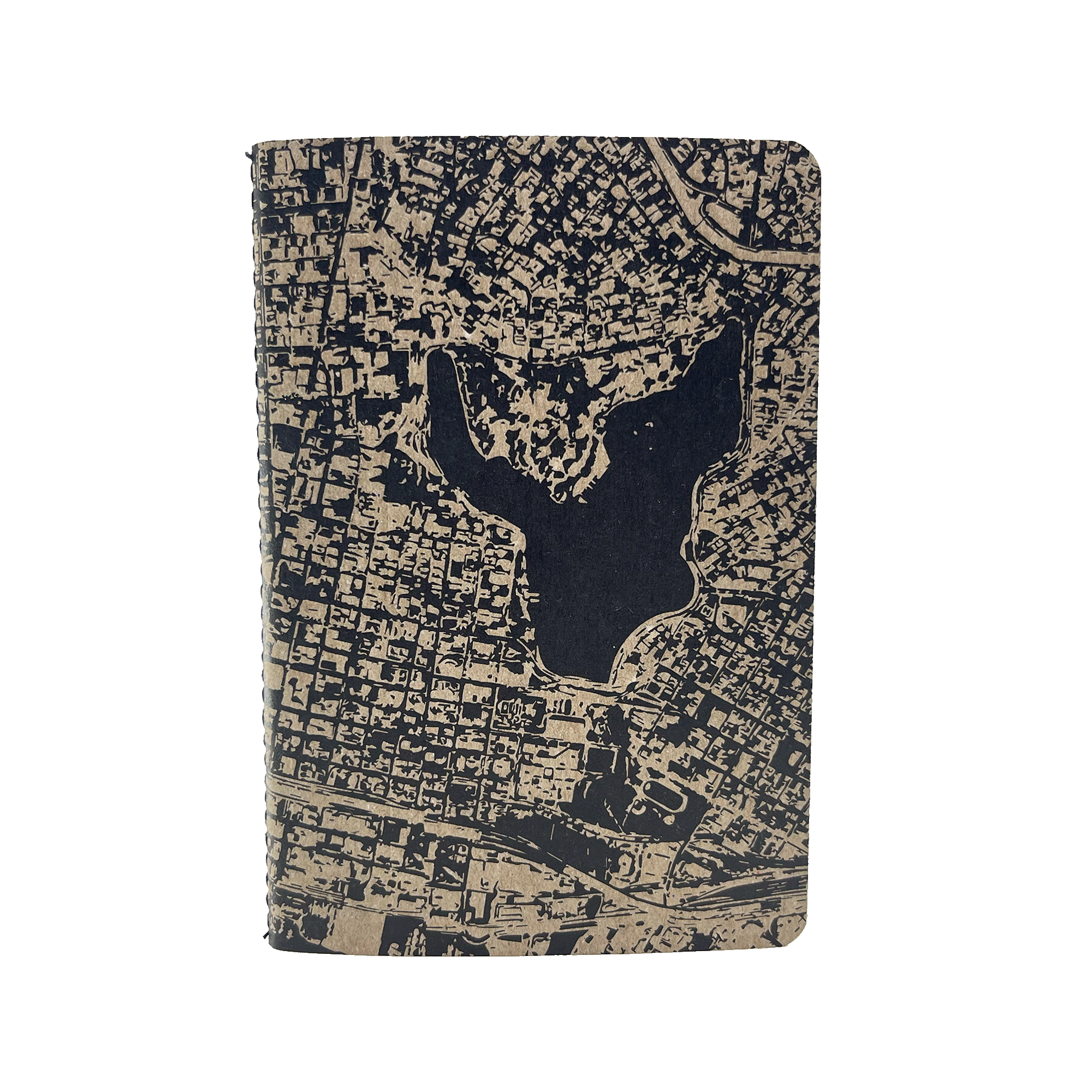 The Aerial Map Mini Notebook by Never Elsewhere features a textured, tan letterpress cover with an intricate black map design. The map showcases a cityscape that includes a central body of water surrounded by a grid-like pattern of streets and blocks. Inside, the dot grid paper perfectly complements the detailed exterior.