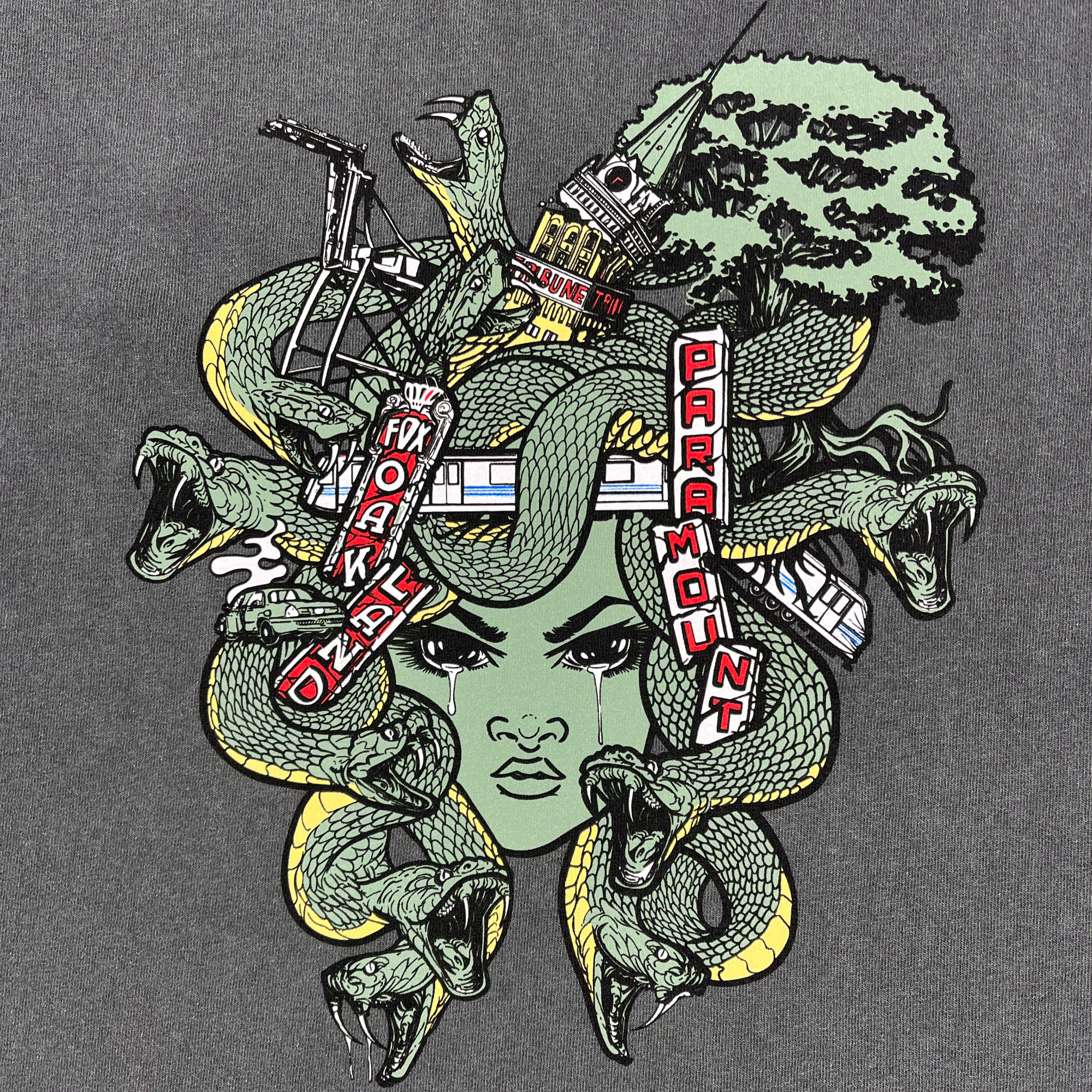 Close-up of green, black, and red Oakland Medusa graphic on the front chest of a faded black women’s tank top.