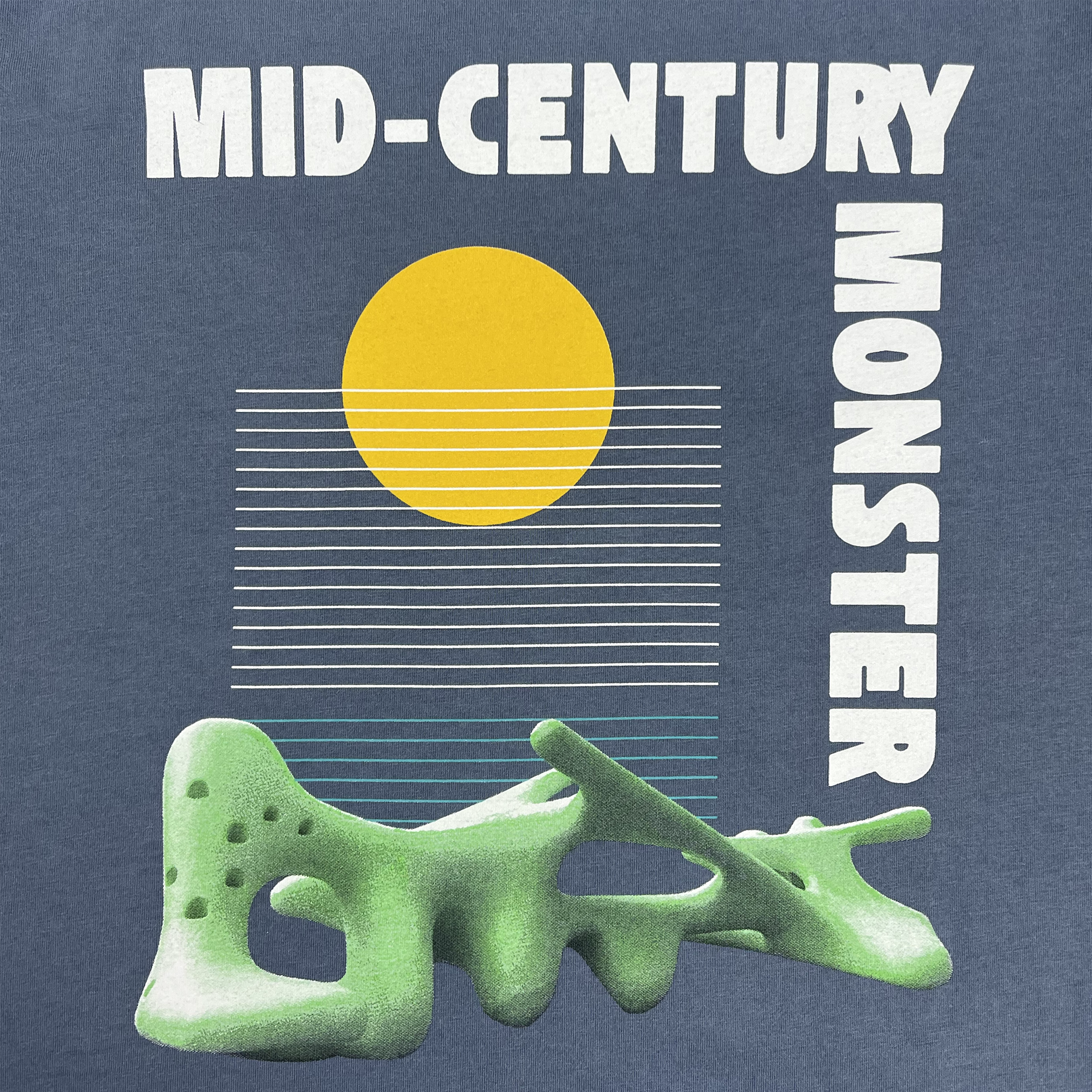 Detailed close-up of mid-century monster graphic from Oaklands Marci Iron Works on the front chest of a faded blue women’s t-shirt.
