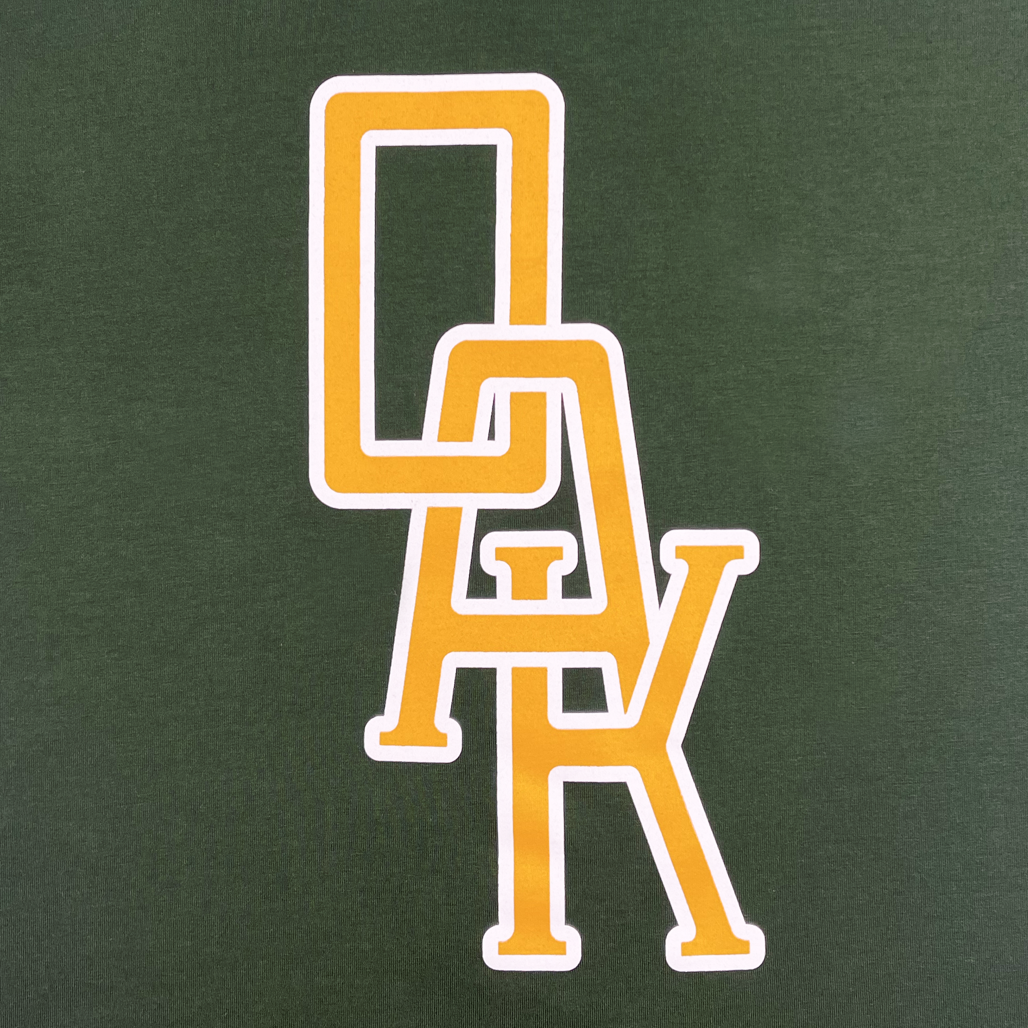 Detailed view of a forest green t-shirt with OAK monogram design centered in yellow and white.