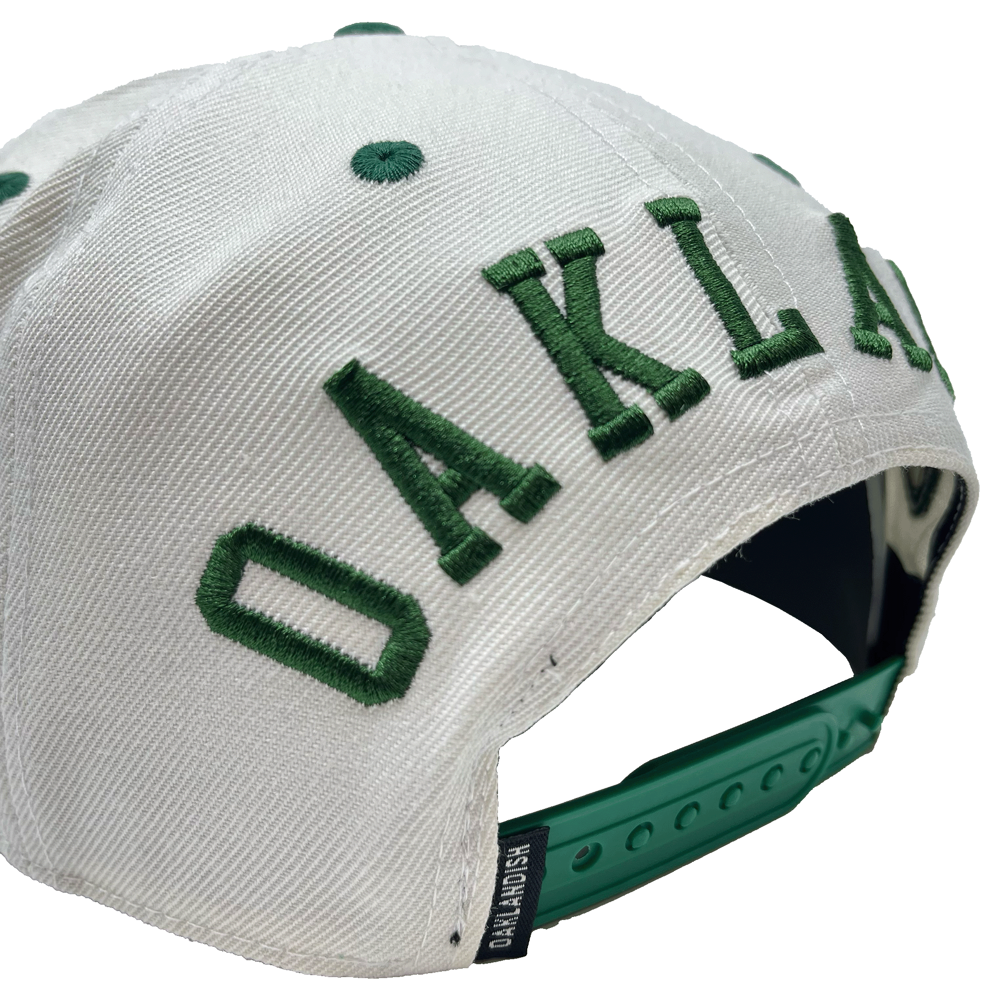 Side-angled back view of a white hat with a green adjustable snapback closure, large green embroidered OAKLANDISH wordmark, and small Oaklandish tag. 