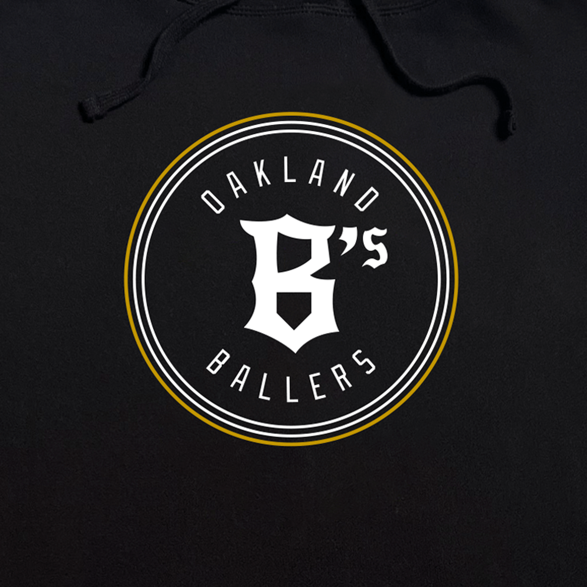 Close-up of round white and gold Oakland Ballers logo and wordmark on the front chest of a black pullover hoodie sweatshirt.