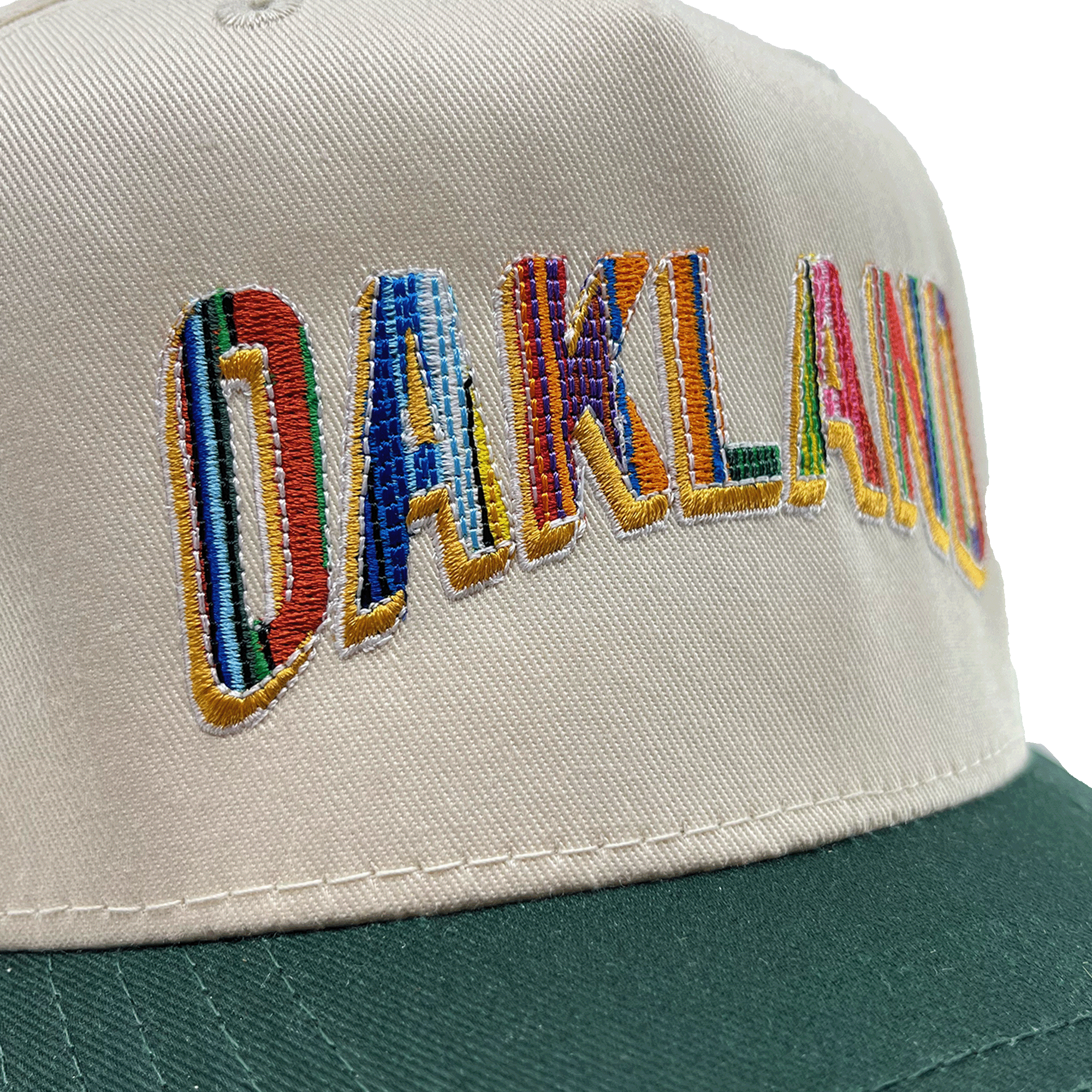 Close-up of the Oakland Ballers’ Oakland Beisbol 5 Panel Cap, featuring bold "OAKLAND" rainbow embroidery and a dark green brim, shown on a plain white background.