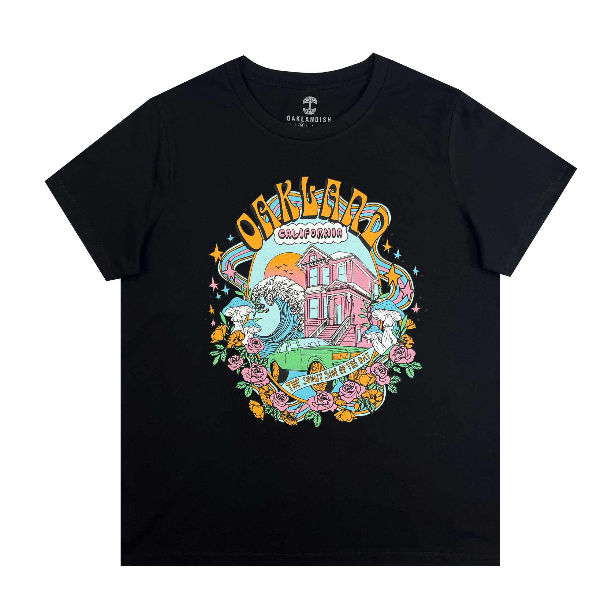 The Women's Oakland Dream Tee from Oaklandish is a black classic fit t-shirt showcasing a colorful design with "Oakland, California" boldly curved at the top. Below it is a vibrant scene featuring a pink house, crashing waves, roses, and sunflowers. A yellow banner at the bottom reads, "The Sunny Side of the Bay." The brand name "Oaklandish" is placed at the neckline.
