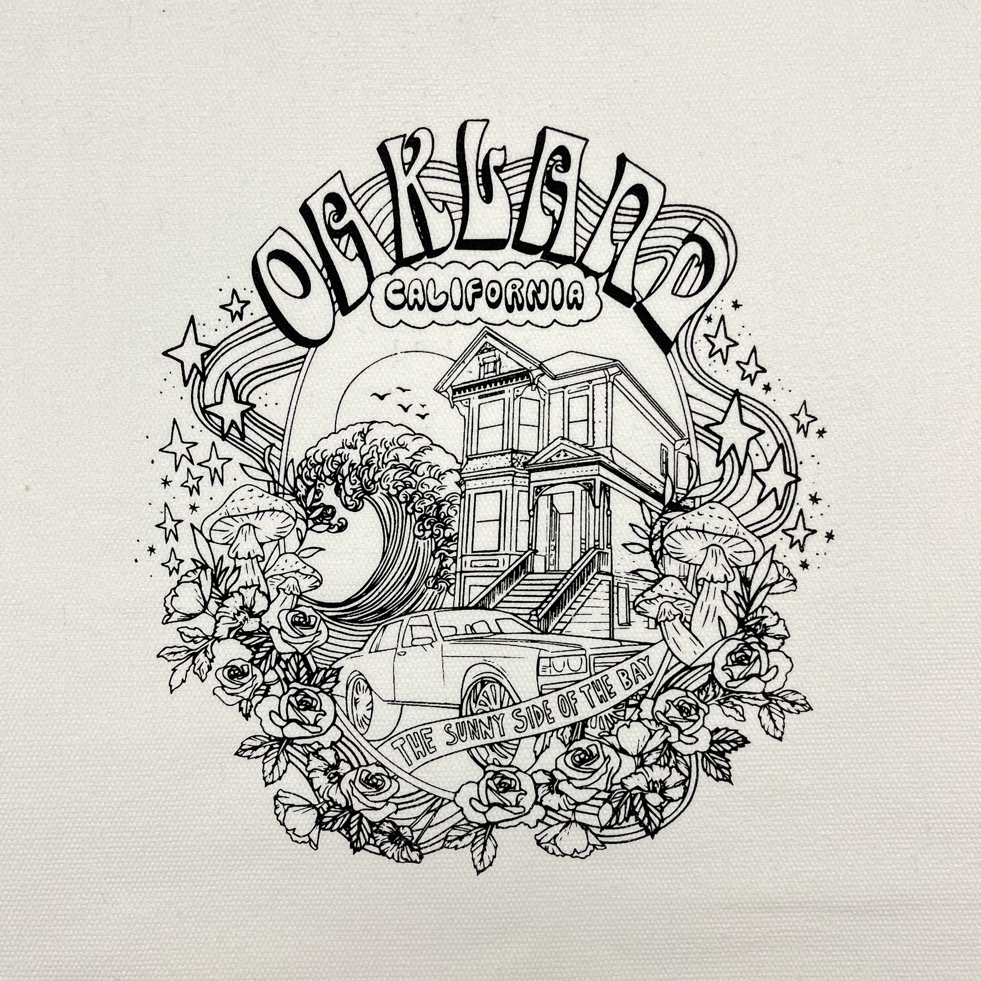 The Oakland Dream Tote by Oaklandish features illustrated artwork of a Victorian house, a classic car, and a large wave adorned with various flowers and mushrooms. At the top, "Oakland California" is written in stylized text. Below the car, a banner reads "The Sunny Side of the Bay." Stars and swirls add to the charm of this delightful canvas tote bag.