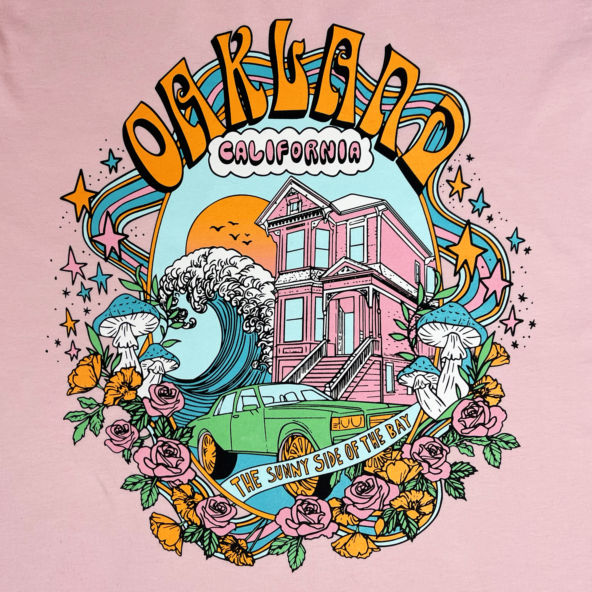 Close-up of Oakland Dream multi-color graphic on the front chest of a pink t-shirt.