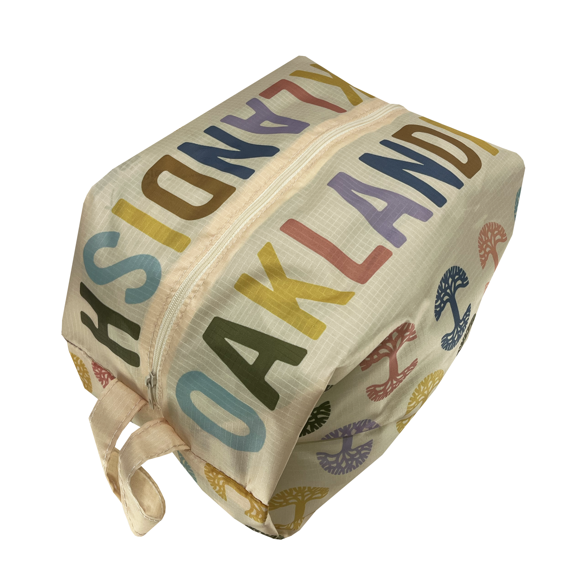 Side view of a natural cream-colored zippered toiletry dopp bag with multi-color Oaklandish tree logos on repeat and Oaklandish wordmarks on the top.