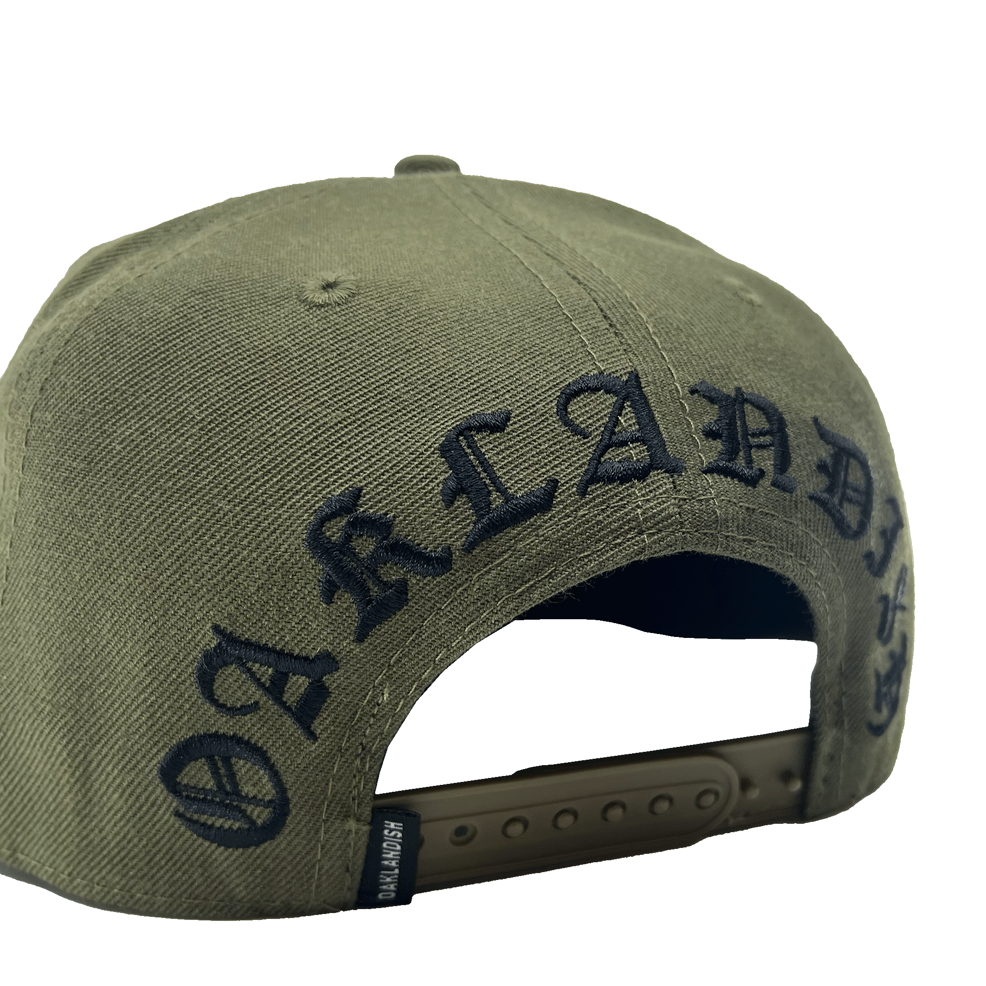 The Old English Aft Snapback by Oaklandish is an olive green hat featuring the word "OAKLANDISH" embroidered in black, gothic-style lettering across the back. This adjustable snapback has a dark green strap with multiple notches and a textured fabric for durability. The iconic Oaklandish tree logo adds a signature touch to this stylish cap.