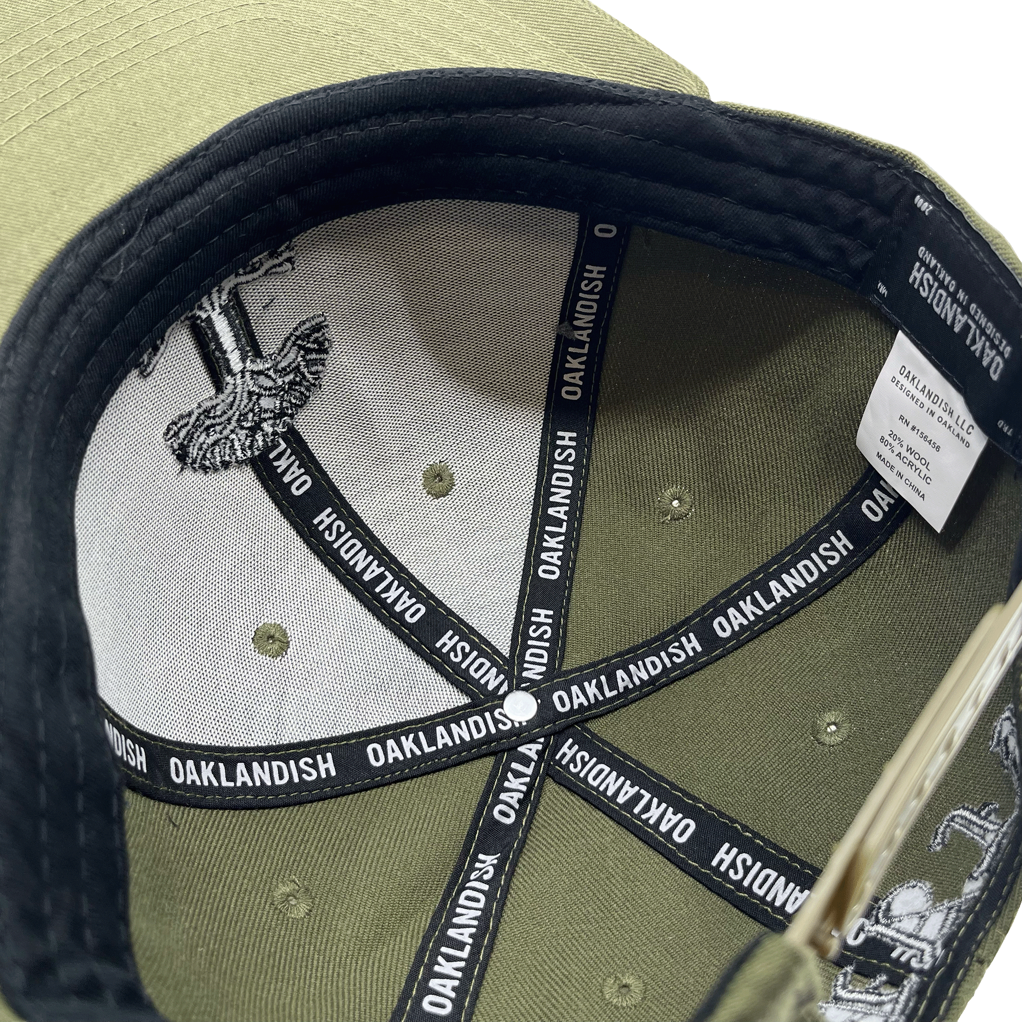 Inside under view of the black Oaklandish taping inside a gree Oaklandish hat. 