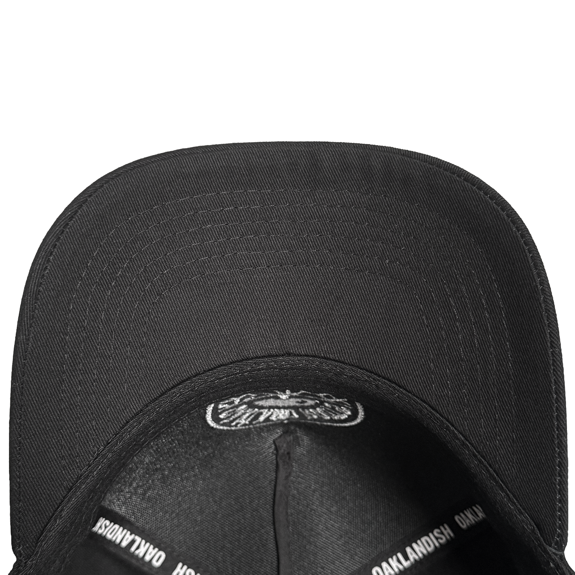 A top-down view of the black ORSC 5 Panel Hat by Oakland Roots SC, showing the underside of its brim and inside panels with "OAKLANDISH" repeatedly printed in white—a standout piece for Oakland Roots SC fans.
