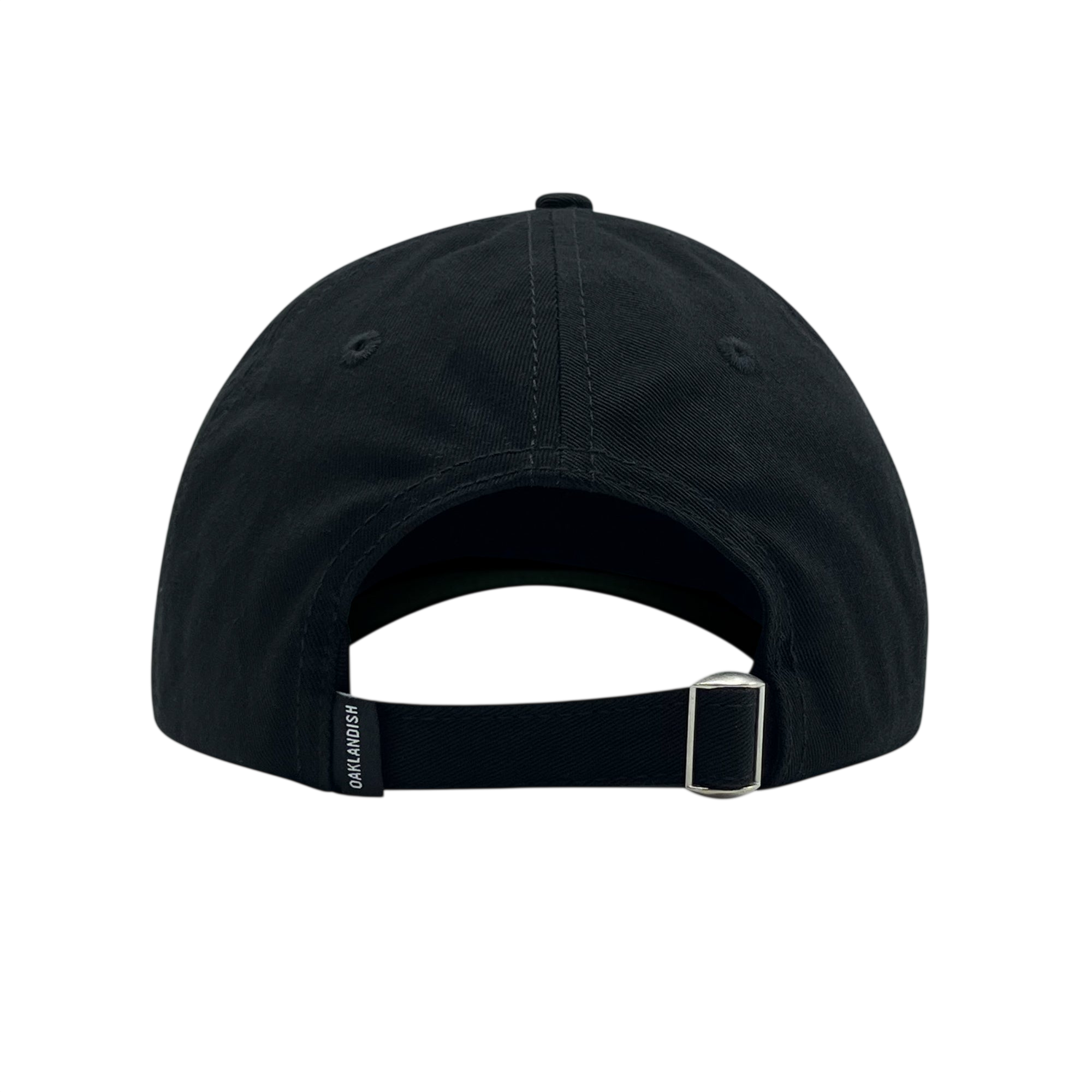 Rear view of the Official Micro Logo Dad Hat by Oaklandish in black. The cap features a central seam with visible stitching, an embroidered "O" on the side, a metal buckle on an adjustable strap, and a small rectangular tag with text on the left side of the strap. The white background highlights the cap's intricate details.