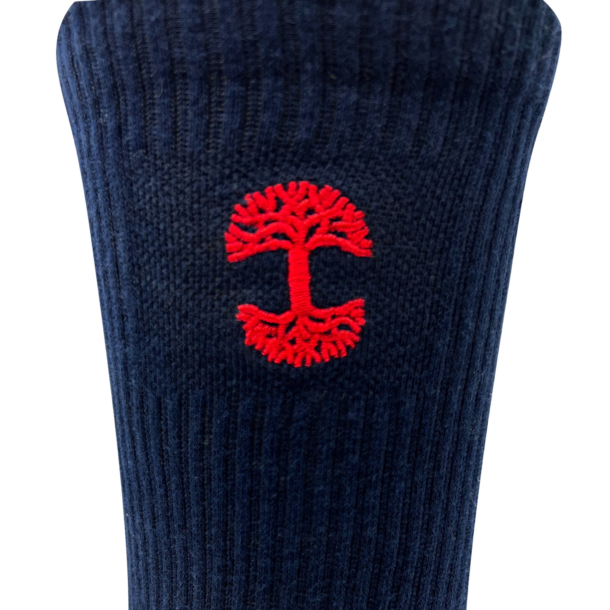 A detailed view of the Embroidered Logo Sock by Oaklandish, showcasing a dark blue ribbed knit fabric adorned with a small red embroidered Oaklandish logo—a stylized tree with mirrored branches and roots forming a circular shape—in the center. The simple background accentuates the fabric and emblem, evoking the timeless style of classic crew socks for adults.