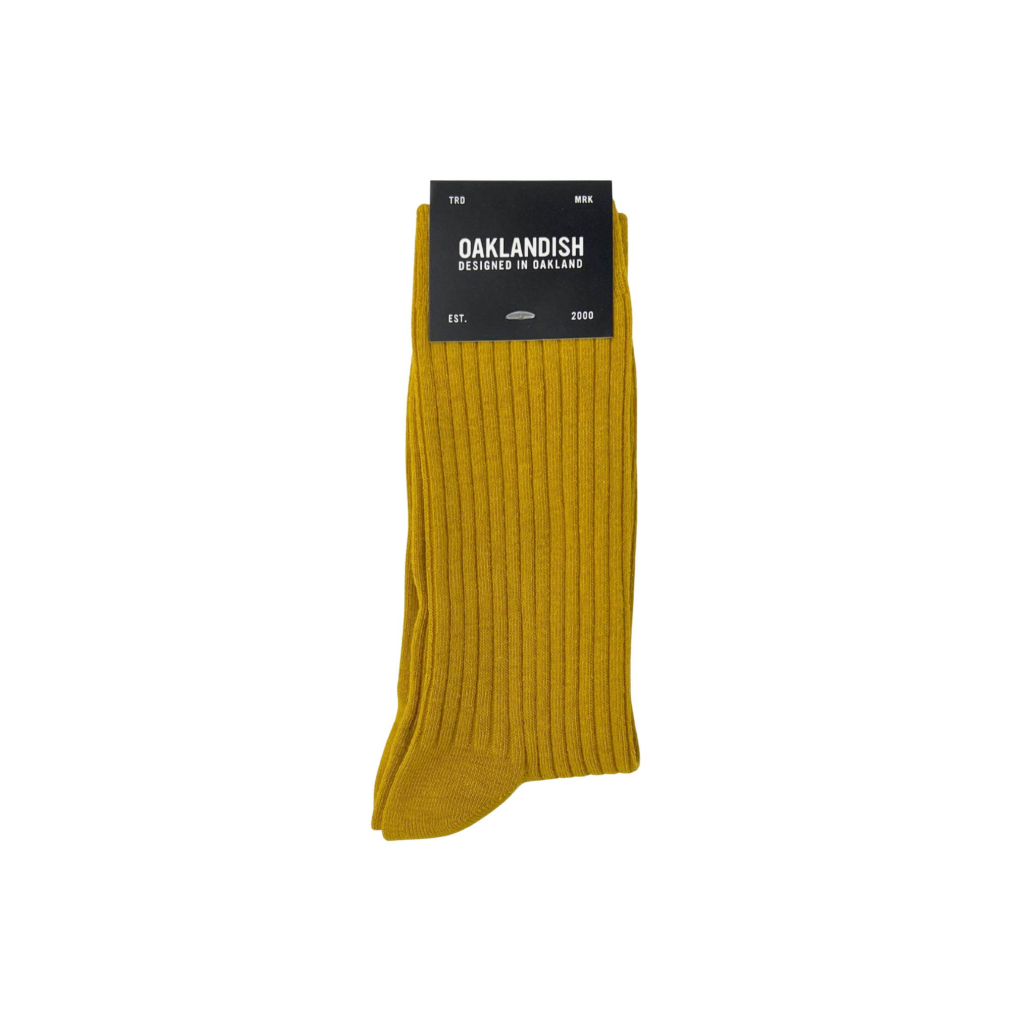 A single pair of mustard yellow Grip Crew Socks from Oaklandish is displayed against a white background. The packaging at the top prominently features the "Oaklandish" brand name in bold white text, along with additional details indicating that these cotton polyester spandex socks are designed in Oakland and available in size M/L.