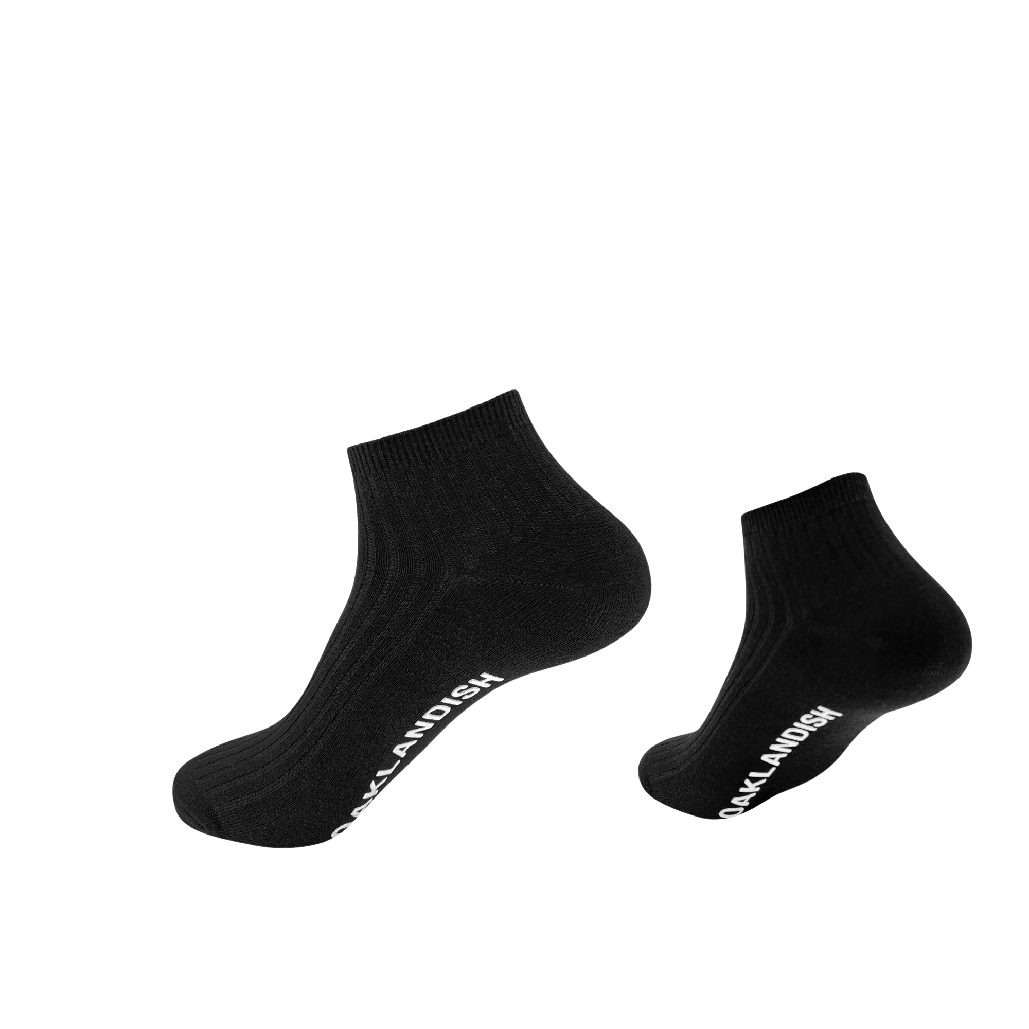 The Grip Low Crew Sock by Oaklandish is displayed against a simple white background. These black socks feature a ribbed texture and have "SOCKLANDISH" written in white text along the outside of the arch. The socks appear to be slightly floating, casting shadows on the surface below them.