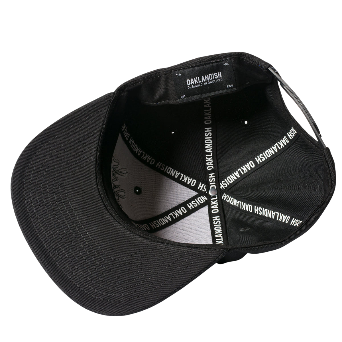The Oaklandish Classic Snapback is shown from the underside, revealing its interior details. The inside features a black fabric lining adorned with white text that reads "OAKLANDISH" repeatedly along the seams. An adjustable snapback strap is visible at the back, and the inside tag also reads "OAKLANDISH.