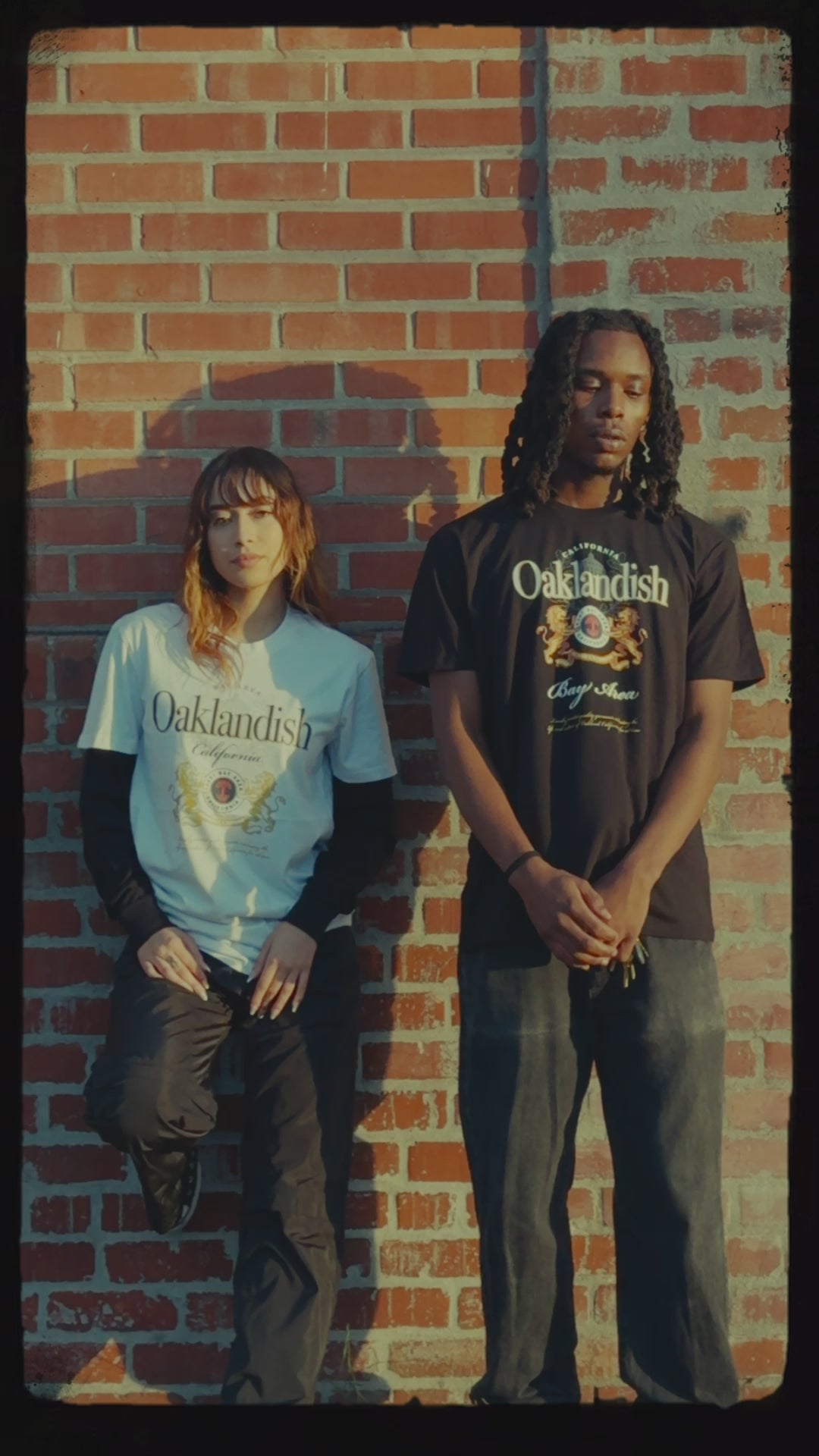 Male and female models wearing our two lager designs posing outdoors against a brick wall.