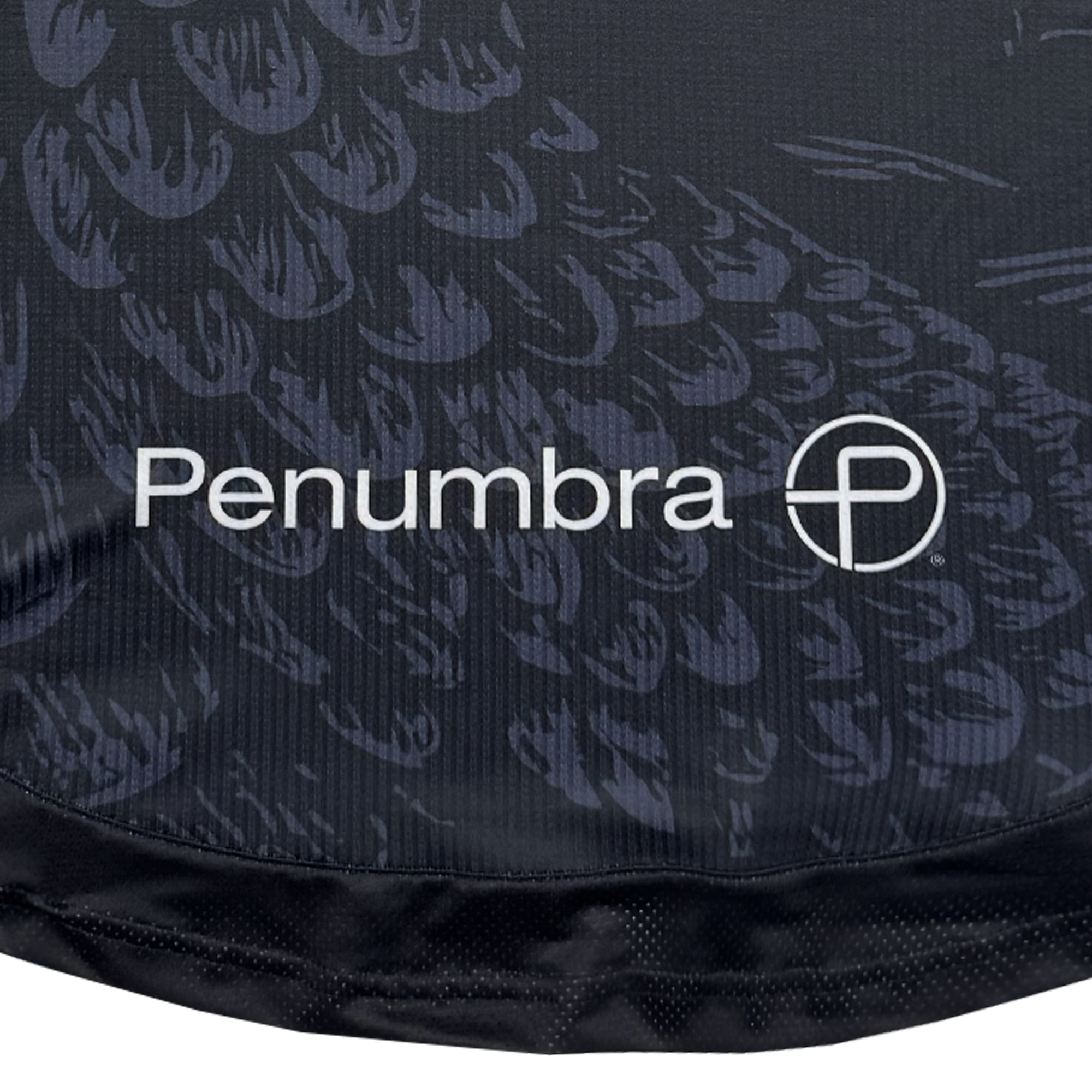 Close-up of black fabric with a feather-like pattern from the Unisex Oak-ness Awakens Kit by Oakland Roots SC. White "Penumbra" text and circular logo evoke legends like the Oak-ness Monster said to dwell in Lake Merritt. Crisp, modern design.