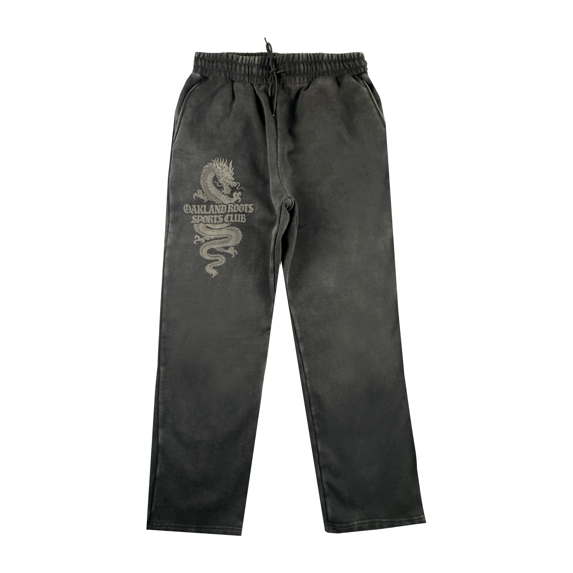 The Tatsu Pants by Oakland Roots SC are black organic cotton sweatpants with an elastic waistband, drawstring, side pockets, a relaxed straight-leg fit, and a light dragon graphic plus "OAKLAND ROOTS SPORTS CLUB" on the left thigh.