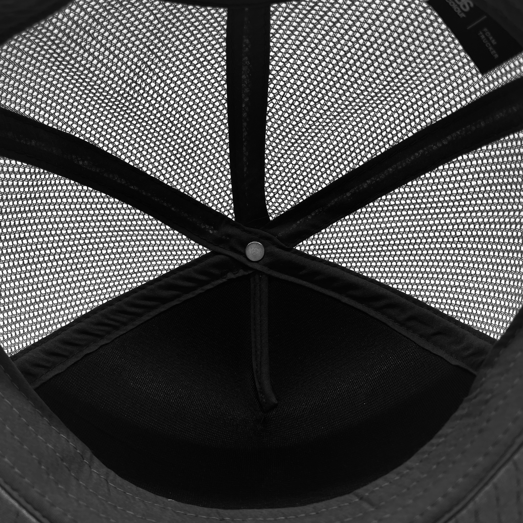 Underside view of black mesh crown on a trucker cap.