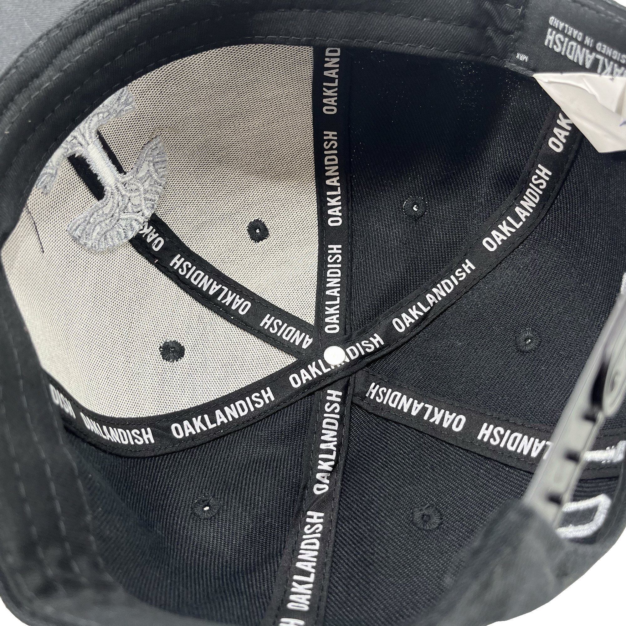View of the inside of the crown with black striping with Oaklandish wordmark on repeat.